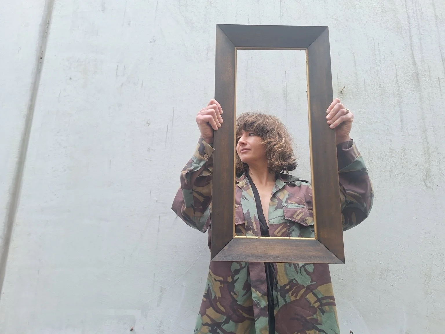Person holding one tall timber frame, showing its scale and gold-coloured inner slip.