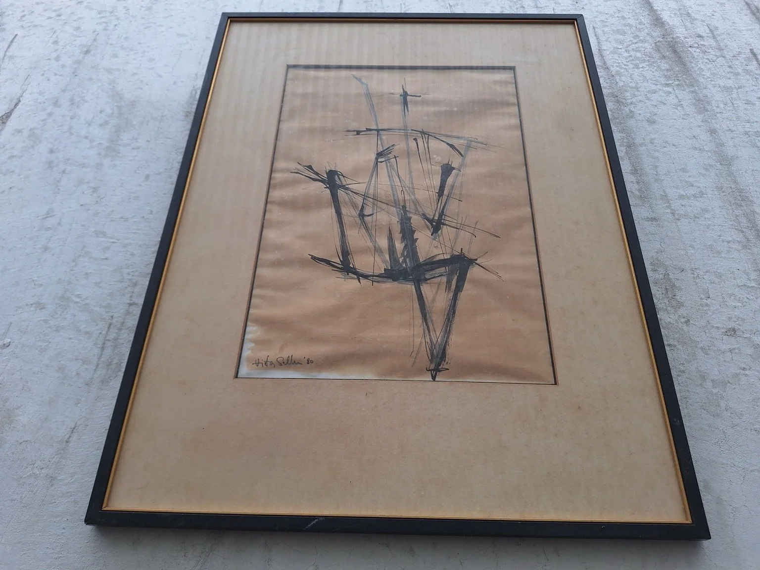 Low-angle view showing rippling to the artwork paper, spotting to the mount and wear along the lower black frame.