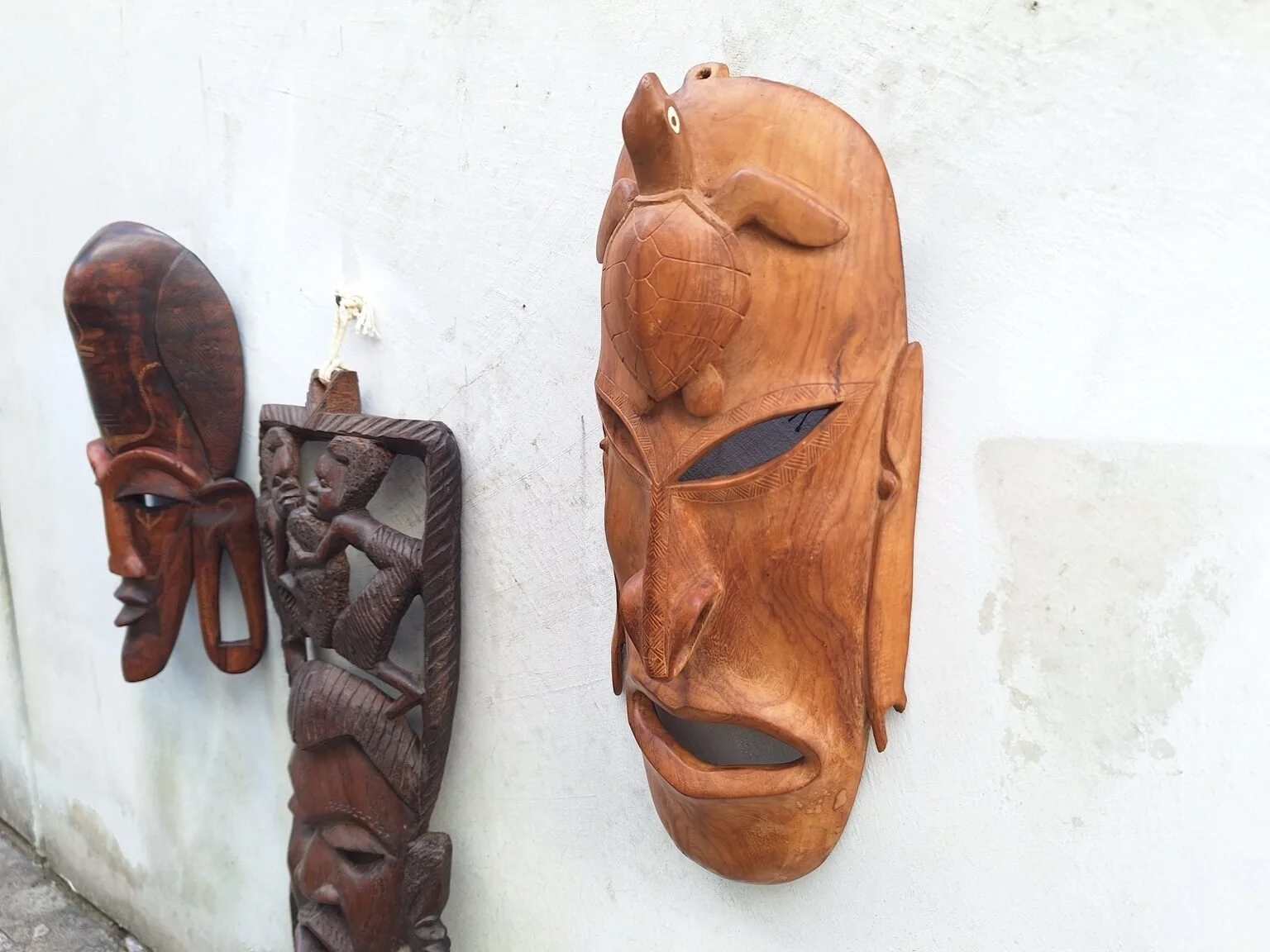 Angled view of the turtle wall mask showing its profile, carved features and broken ear.