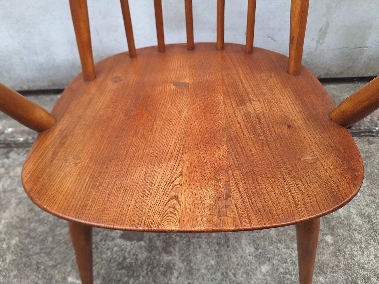 Close view of the timber seat grain and visible surface marks on the Ercol carver chair.