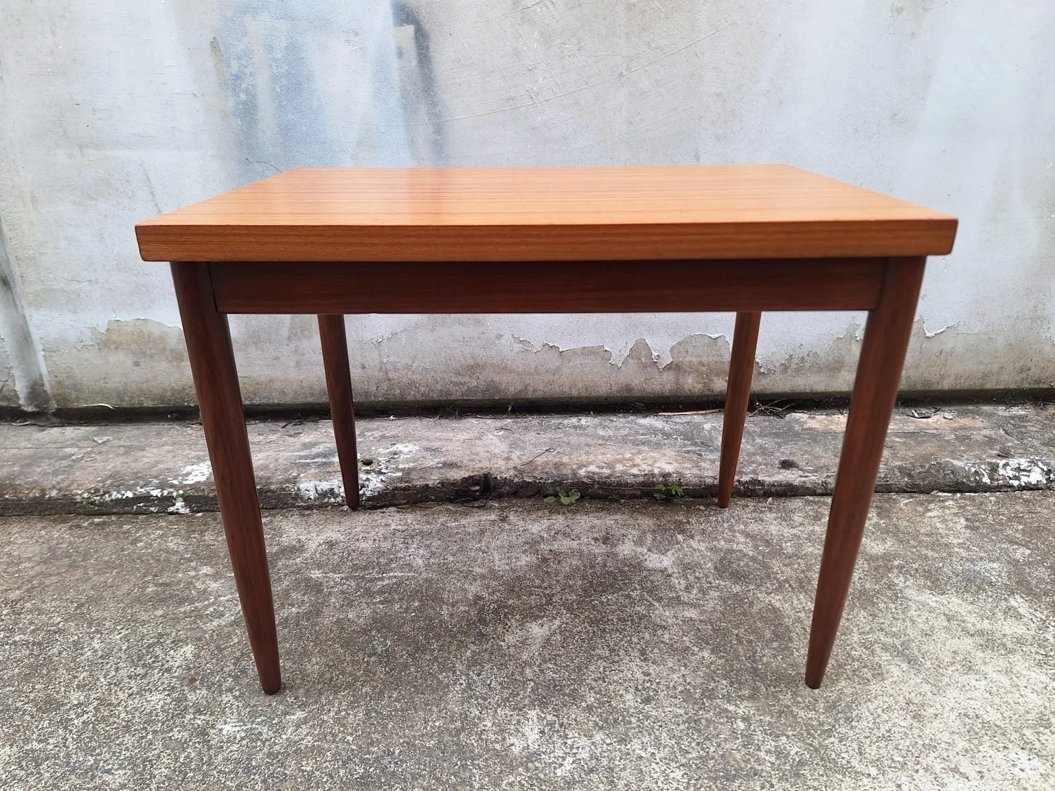 Front view showing the rectangular top and teak base of the side table.