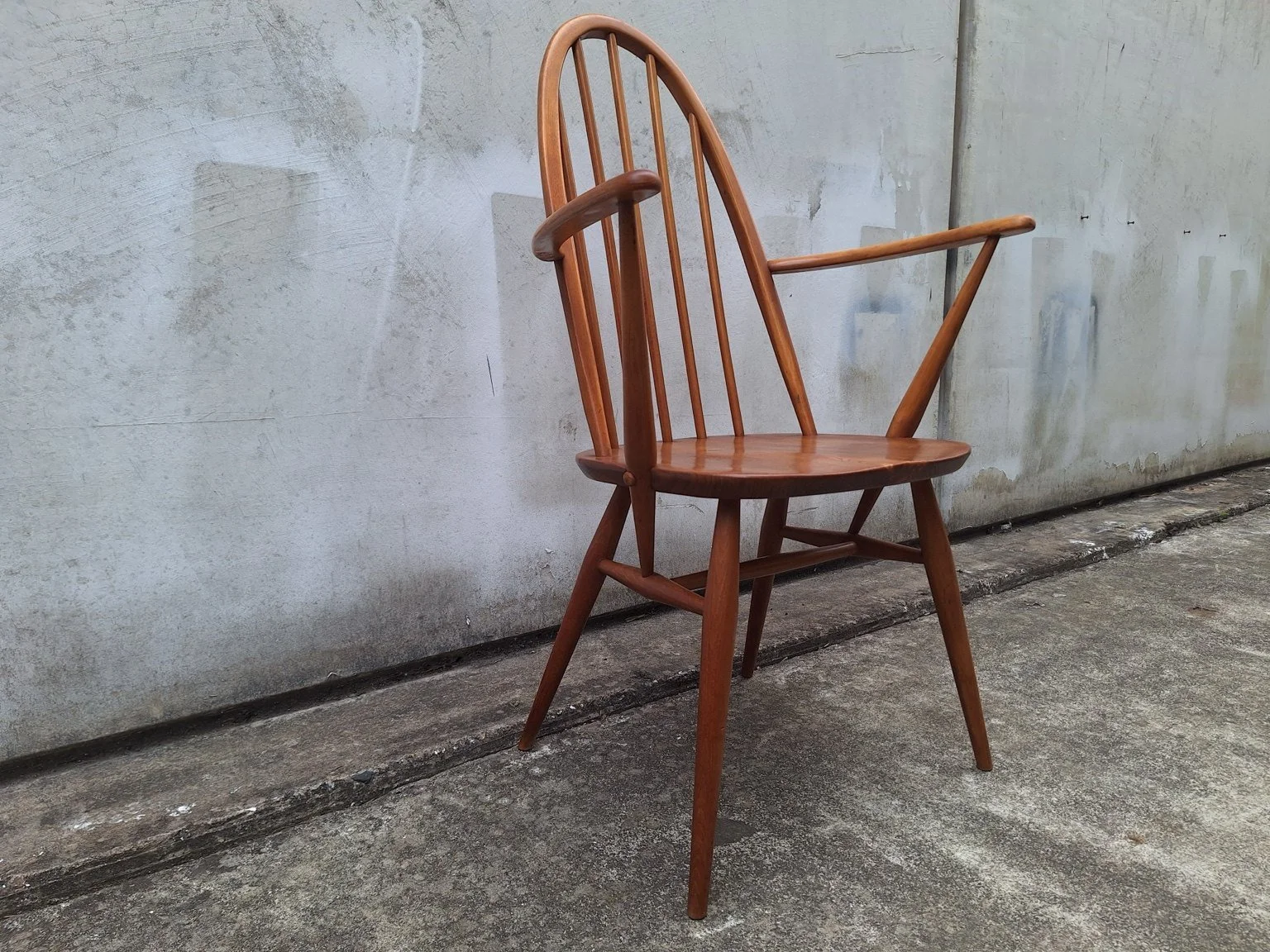 Side view of the Ercol carver chair showing its back profile, arm supports and leg stretchers.