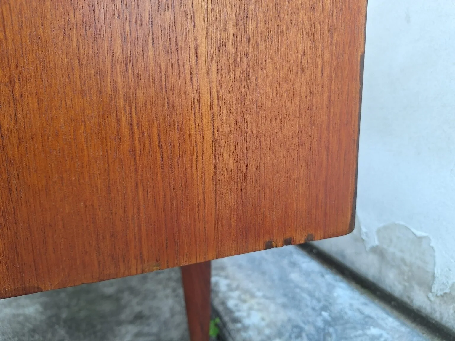 Condition detail showing small repaired areas along the lower edge of the Chiswell sideboard.