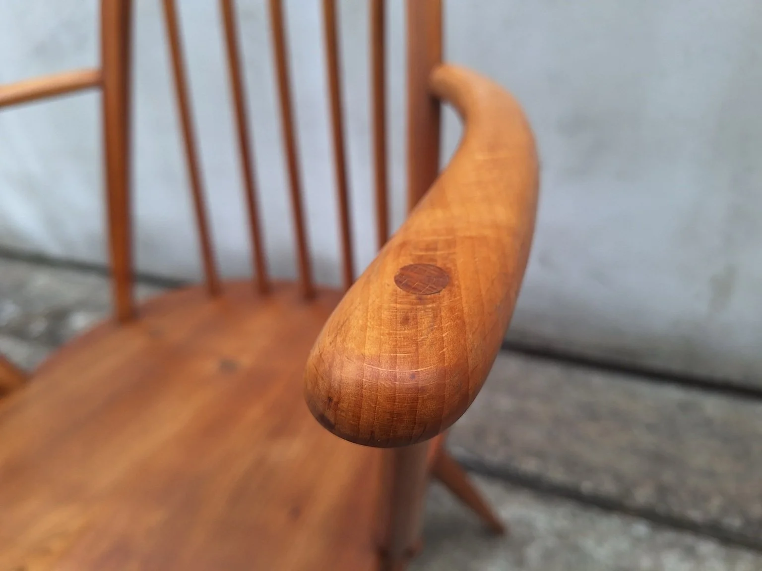 Close view of the rounded timber armrest, visible grain and circular joinery detail.
