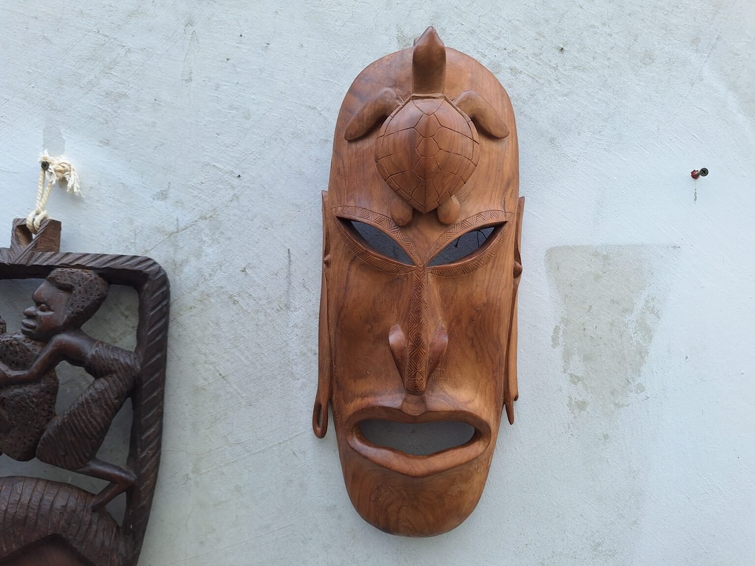 Front view of the lighter timber turtle wall mask with a carved turtle above the face.
