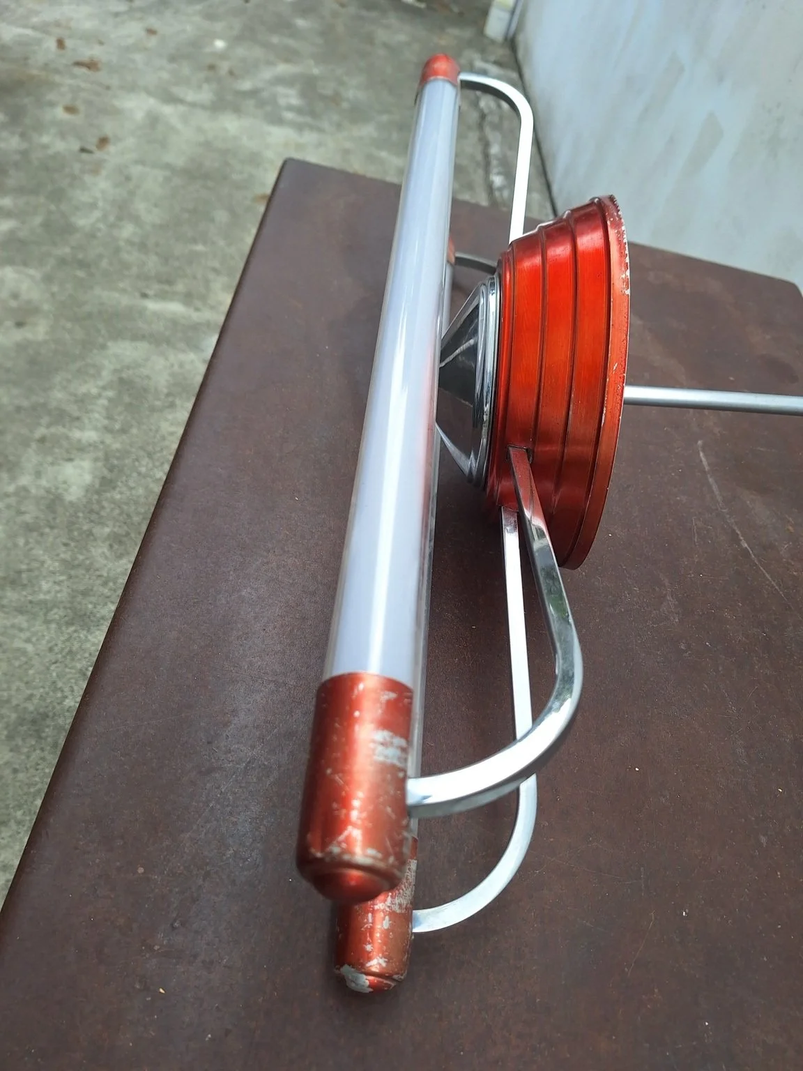 Close side view showing finish loss on the red tube end caps and edge of the central housing.