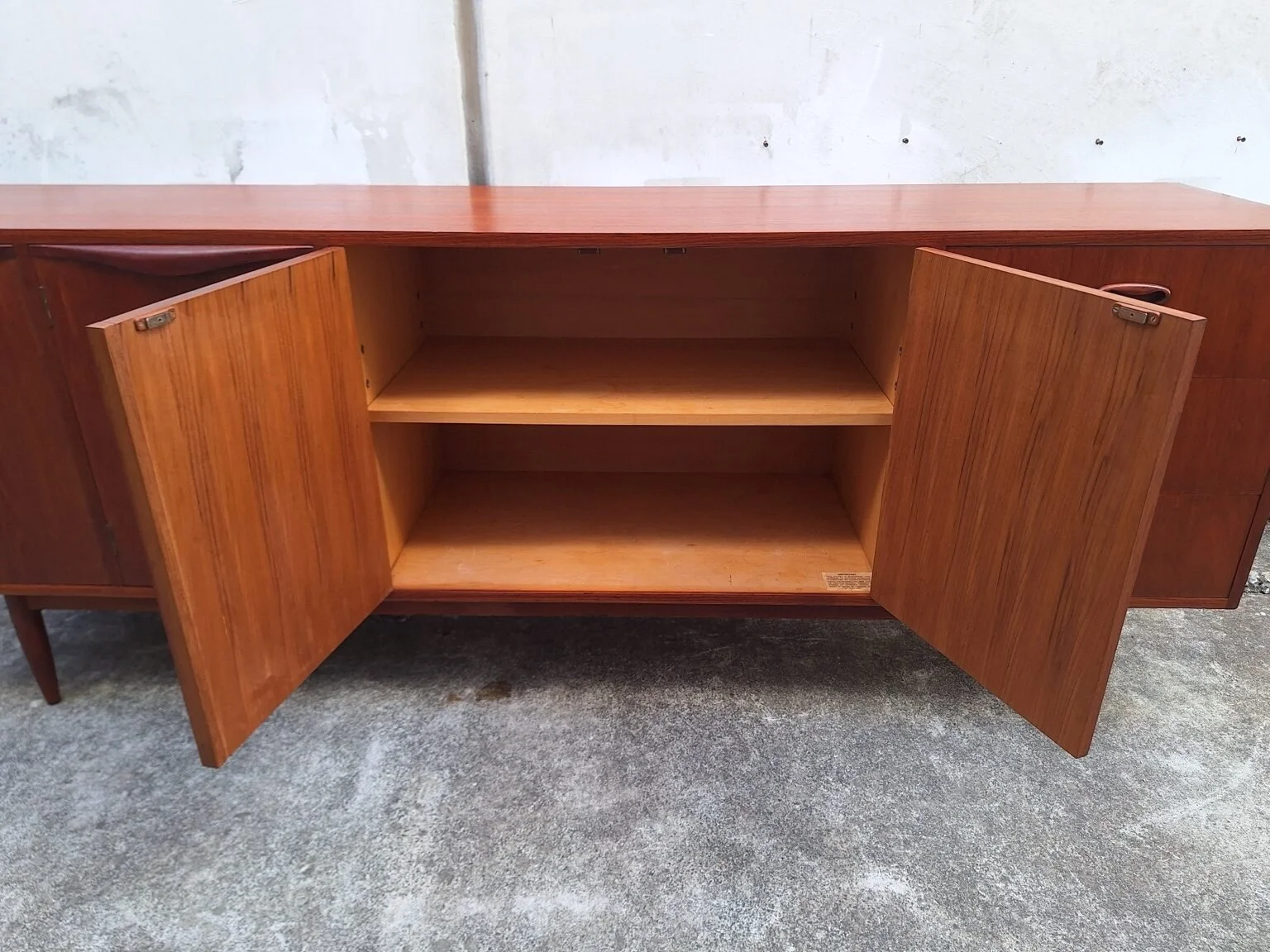 Open cupboard doors showing the internal timber shelving of the Chiswell teak sideboard.
