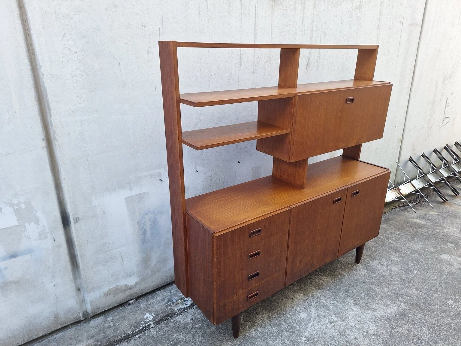 Vintage wall unit viewed from the left, showing its open shelving and drop-down bar cabinet
