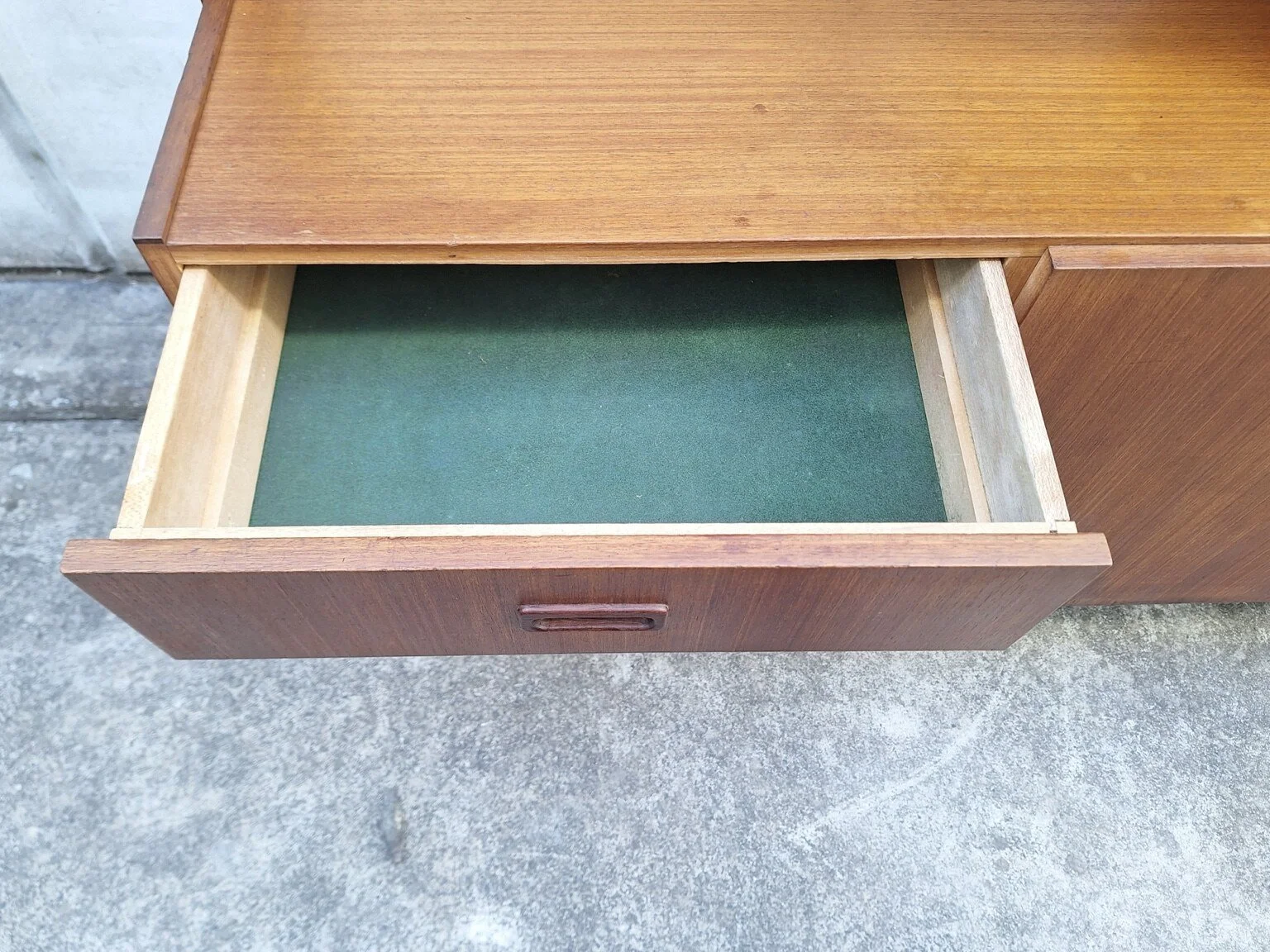 Close view of a green-lined drawer inside the vintage wall unit