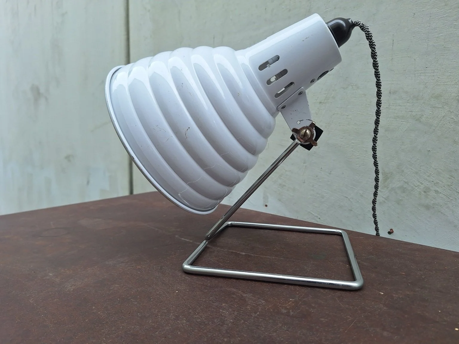 Side view of ribbed white shade and angle-adjustment pivot.