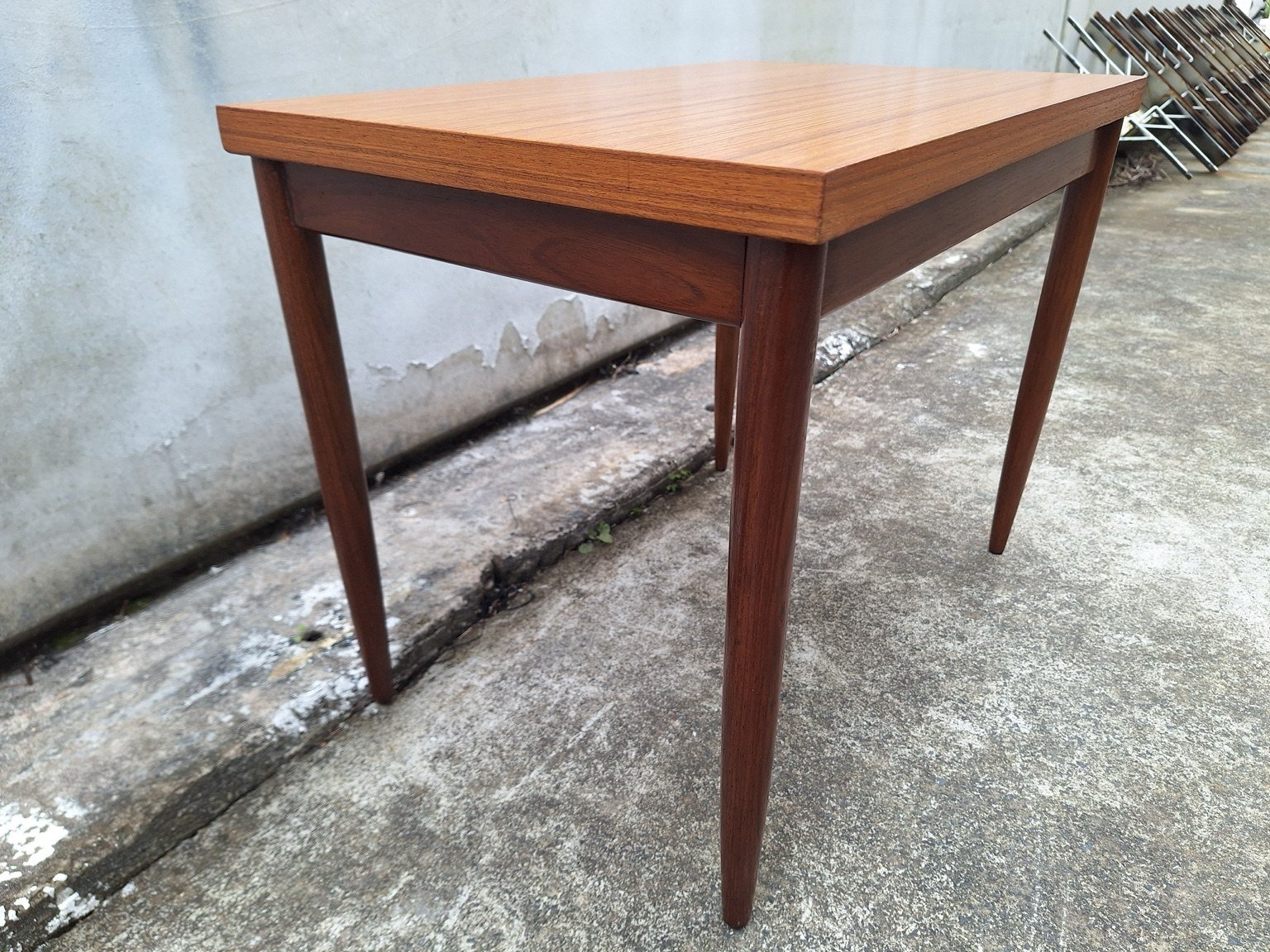 Reverse three-quarter view of the teak base and tapered legs.