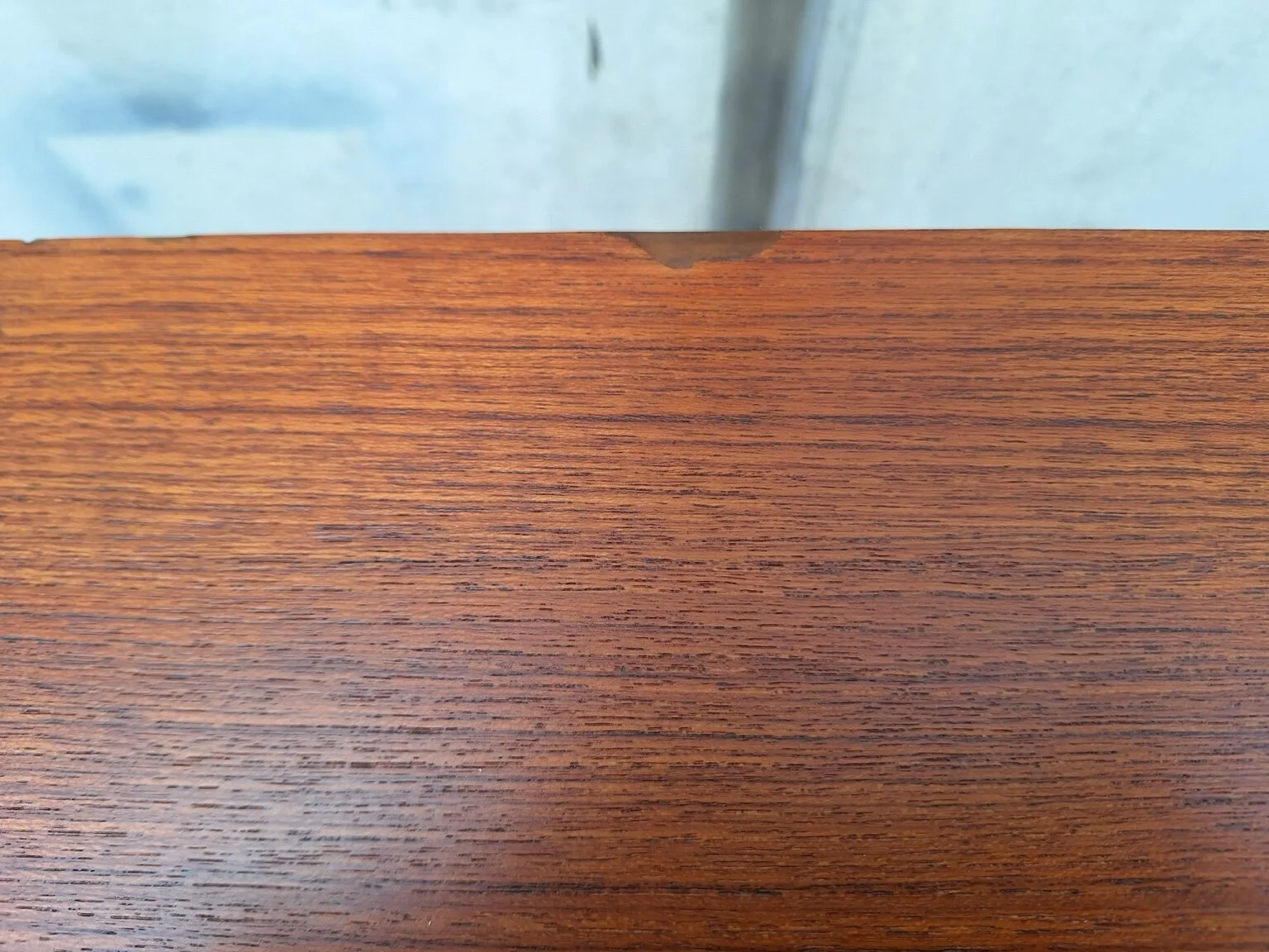Condition detail showing a minor repaired area on the top surface of the teak sideboard.