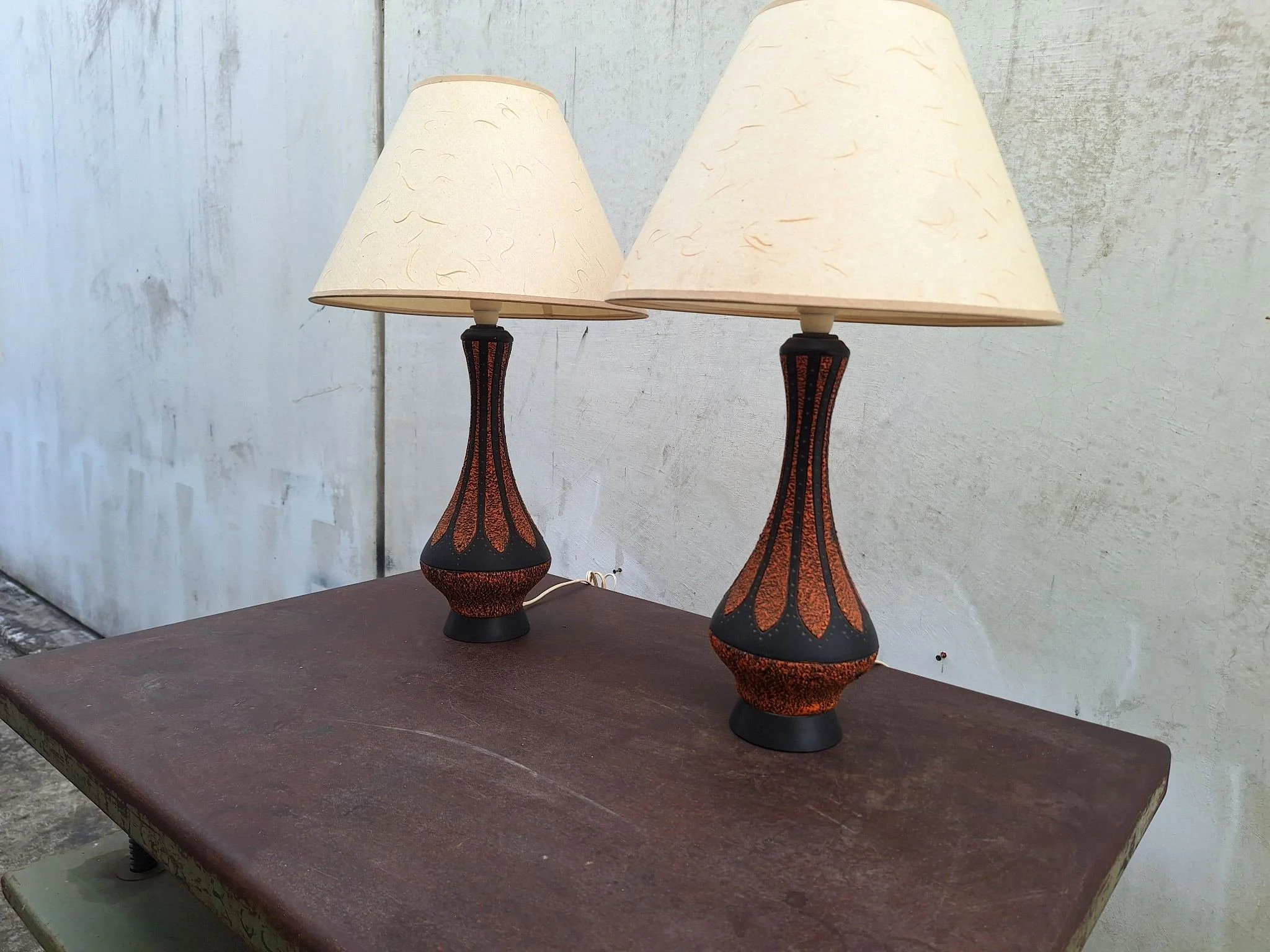 Pair of vintage 1970s plaster table lamps with textured orange and black finish and original shades