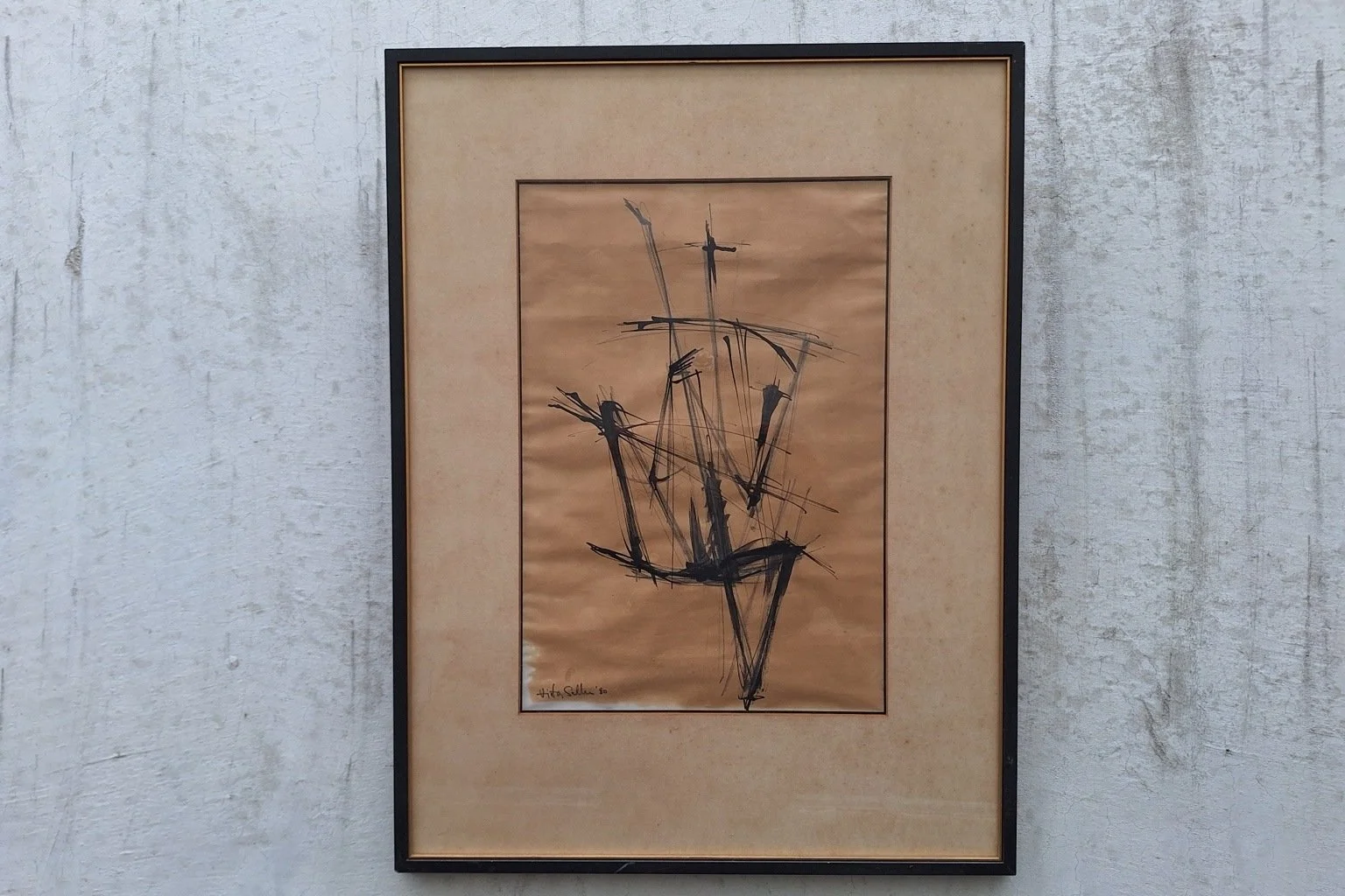 Full view of a signed abstract work on tan paper, displayed in a black frame with a narrow gold-tone inner edge.