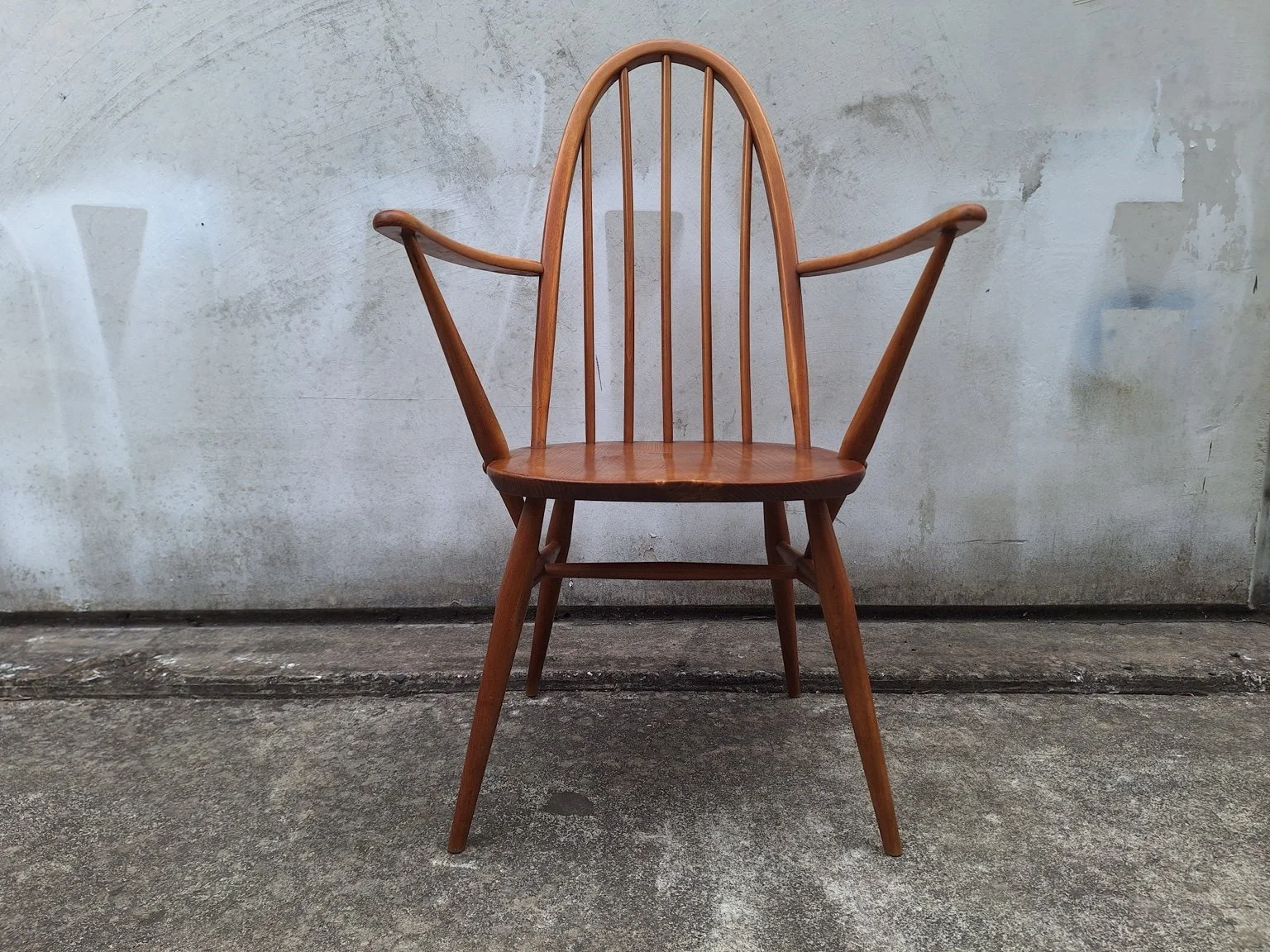 Front view of the Ercol Windsor carver chair showing its arched spindle back, curved arms and splayed legs.