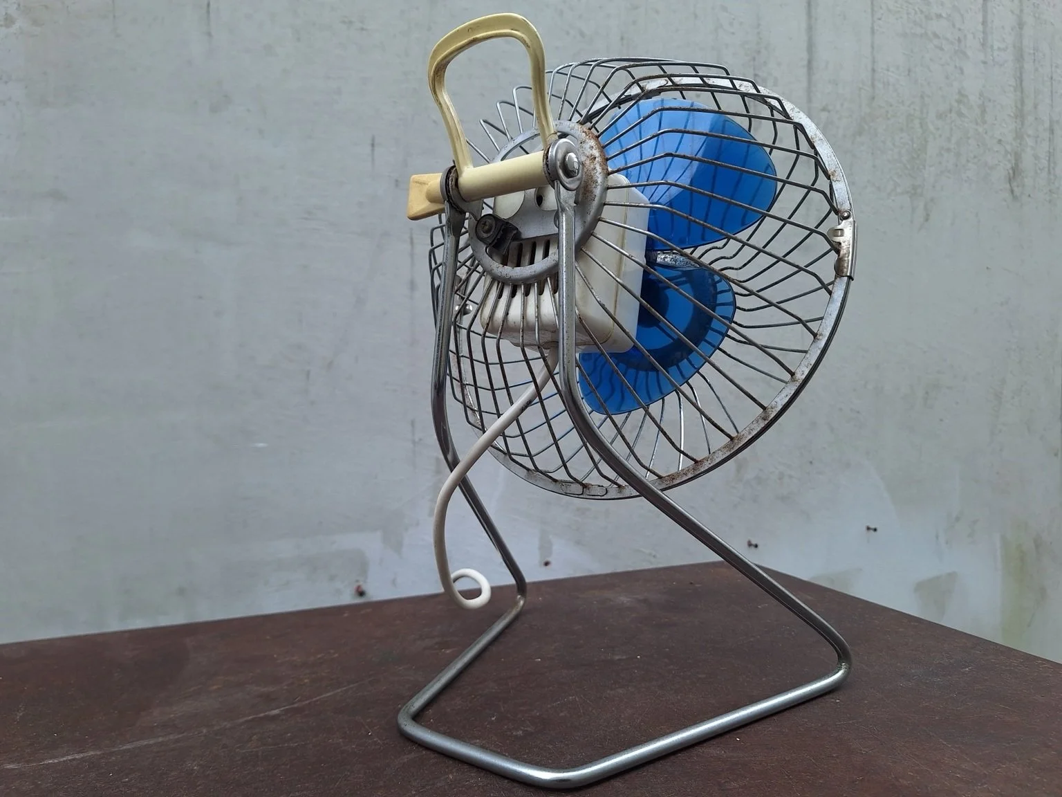 Rear view of the Airmaster fan showing its carry handle, pivot supports and visible surface corrosion.
