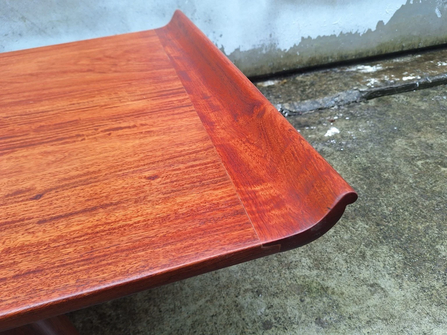Close view of the curved raised end and rosewood grain.