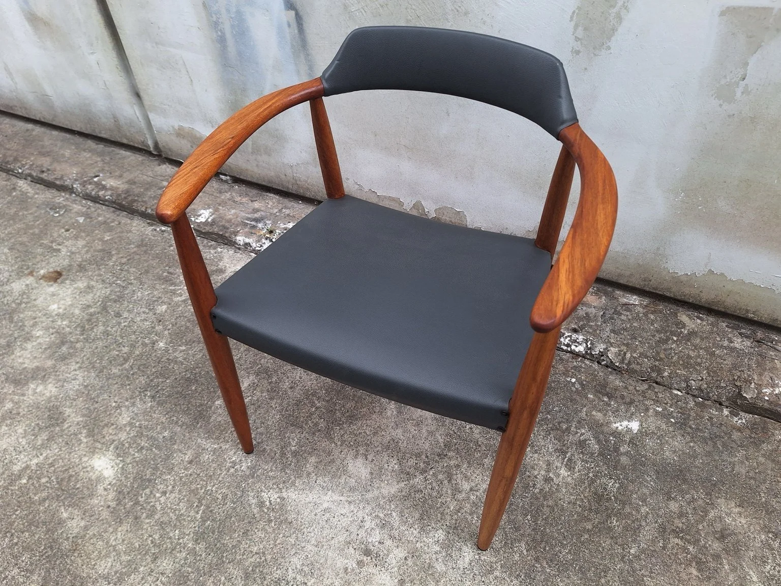 Elevated view showing the upholstered seat and curved timber arms.