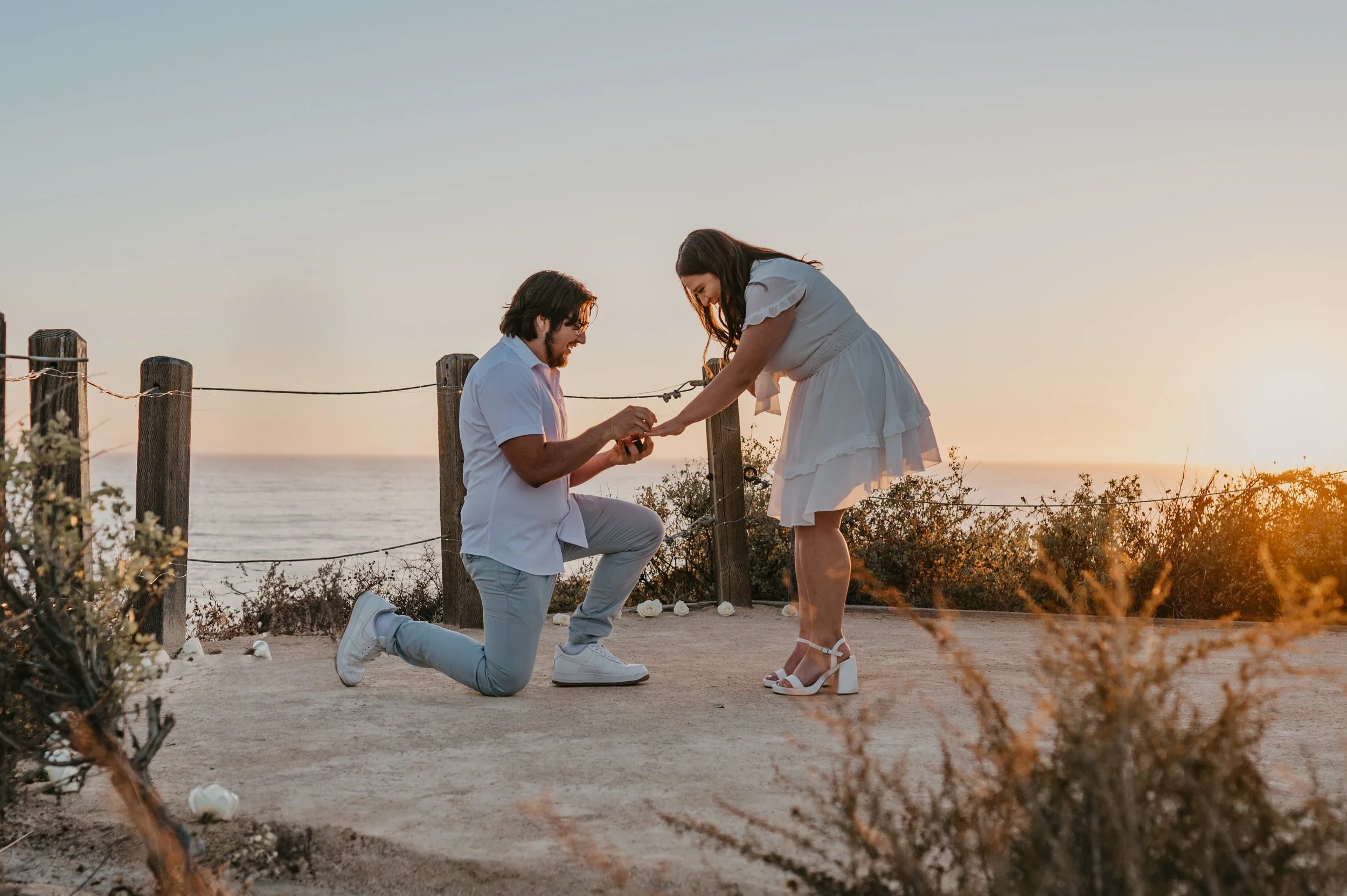 A joyful, surprised reaction to a sunset proposal, with golden light illuminating the cliffs at Crystal Cove State Park