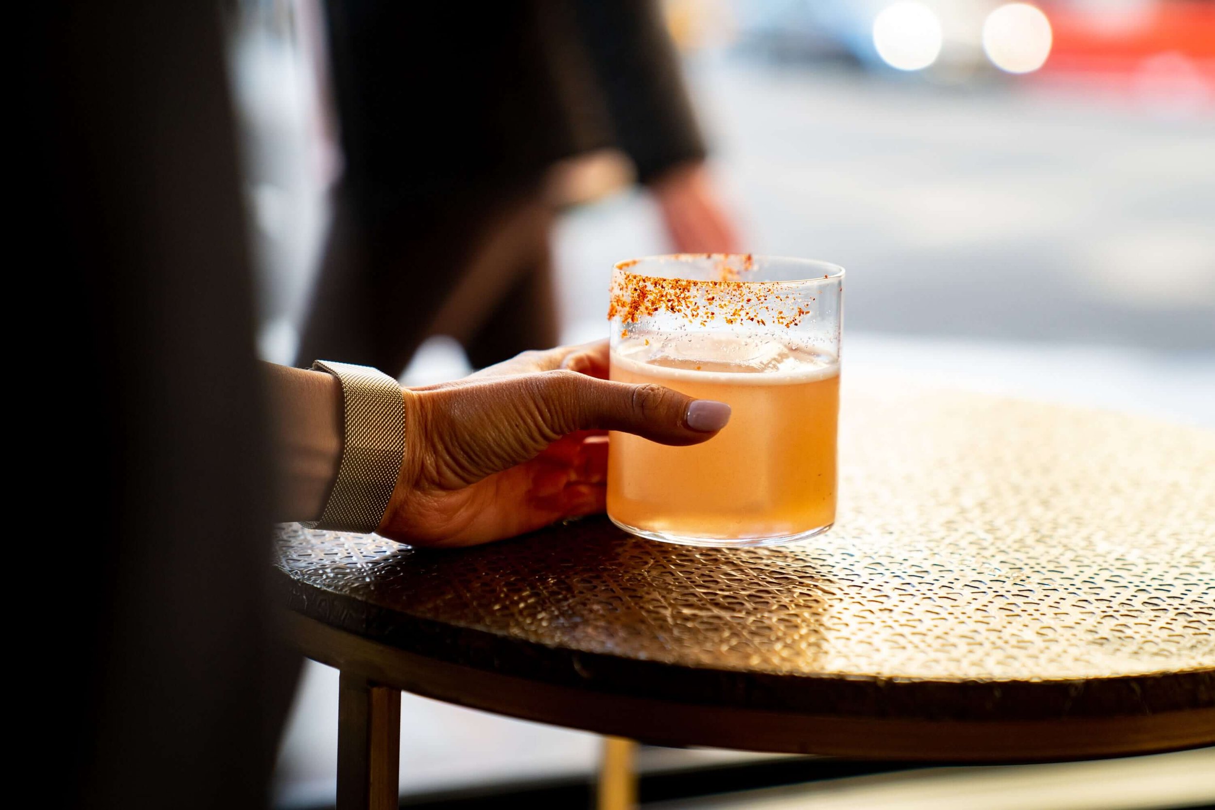 Hand holding a cocktail with a spiced rim