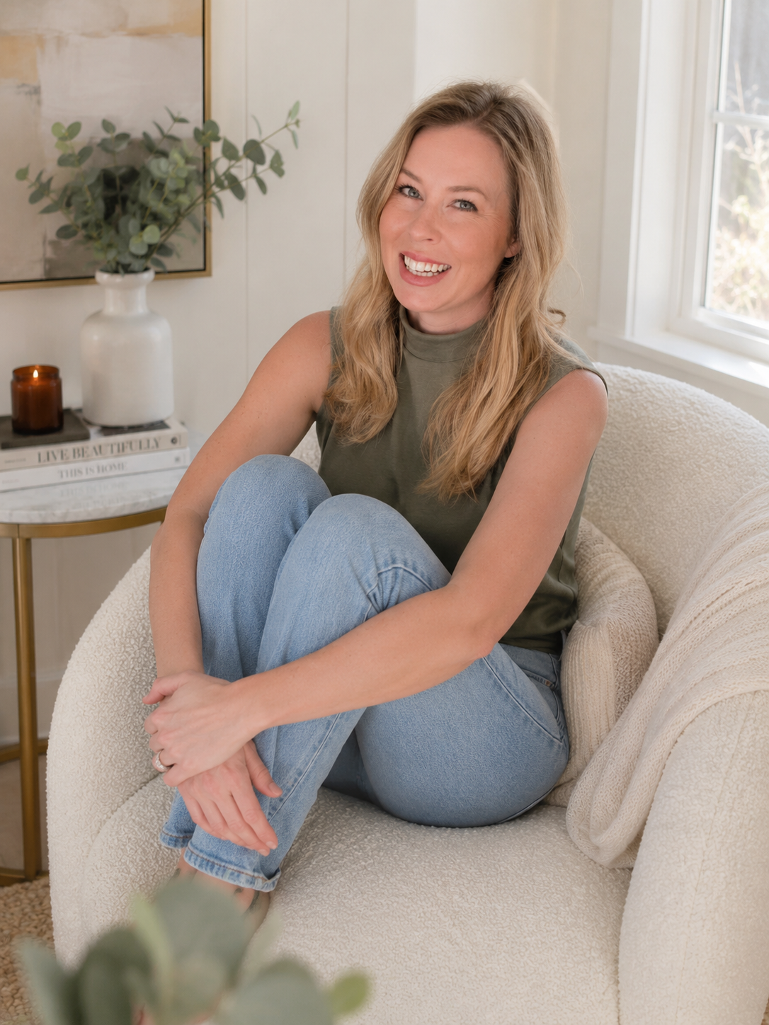 Olivia Radcliffe sitting in a white chair with an olive shirt and jeans