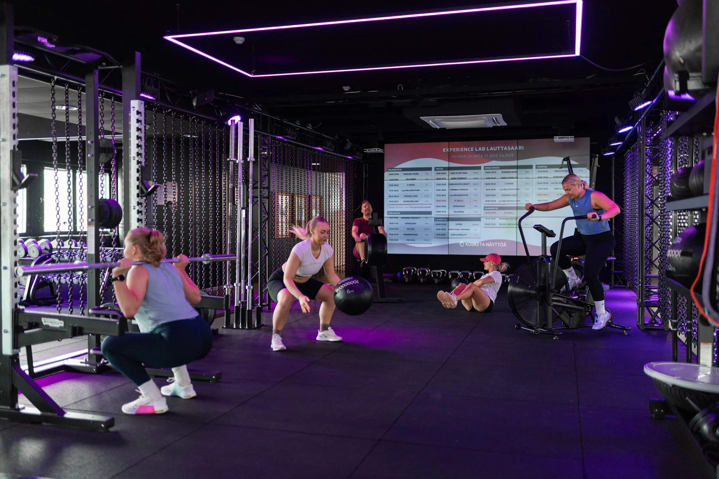 Ihmiset treenaavat kuntosalilla uusilla upeilla kuntosalilaitteilla toiminnallisella alueella