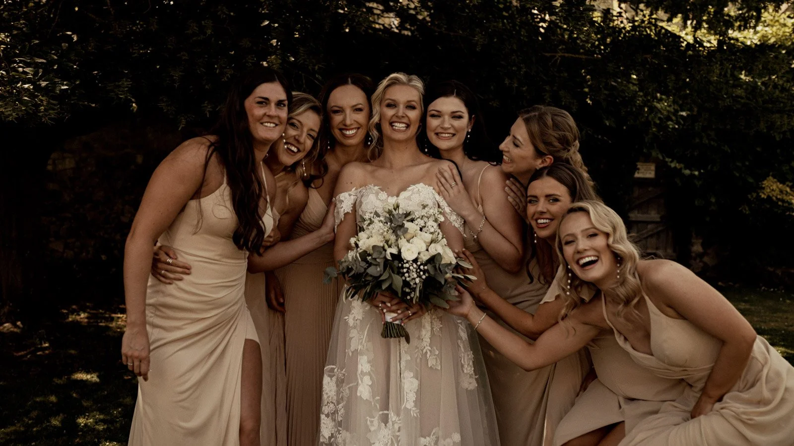 A bride and bridesmaids pose and laugh together during a cinematic Cooling Castle wedding film.