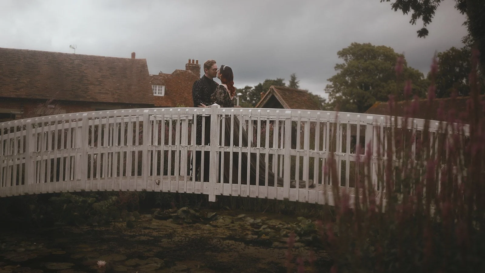 Gothic couple standing on the white bridge in the courtyard of a Winters Barns wedding.