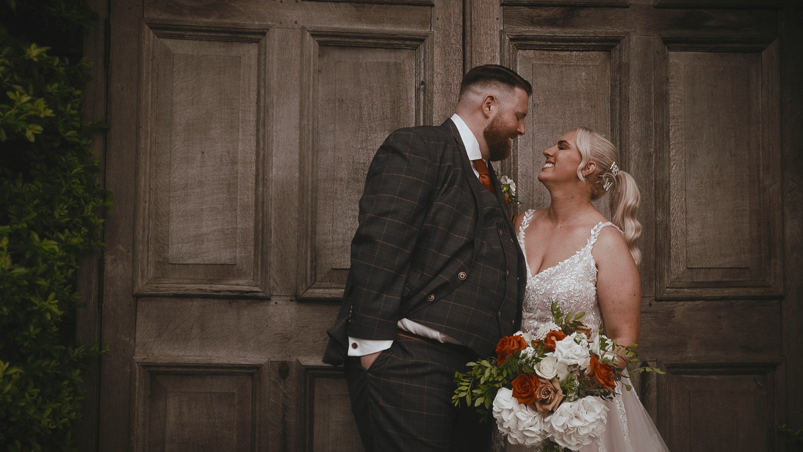 Couple portrait by large wooden doors at Winters Barns during a summer wedding in Kent