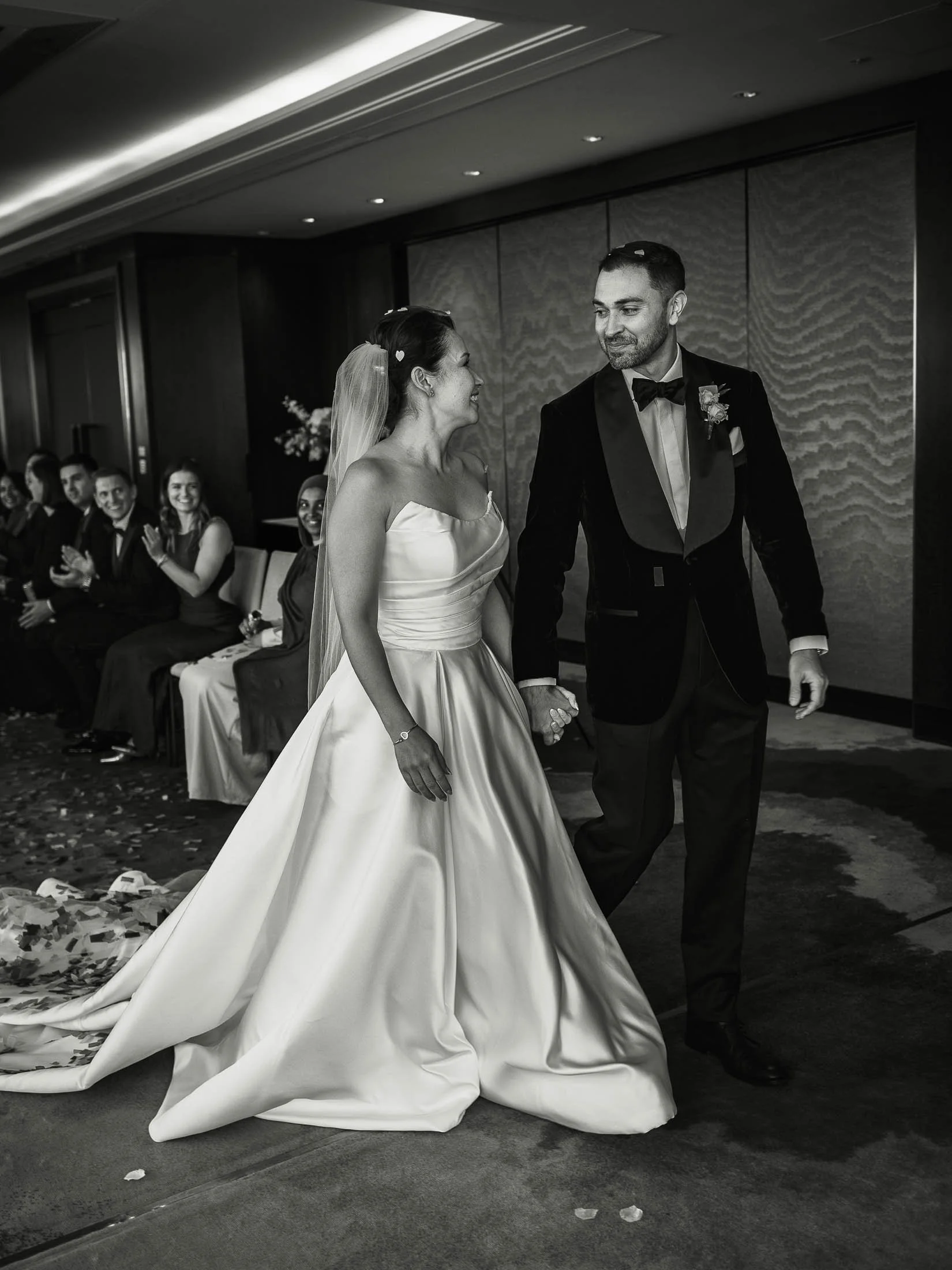 An elegant editorial wedding photograph captured as a bride and groom exit their indoor wedding ceremony at the Shangri-La The Shard.