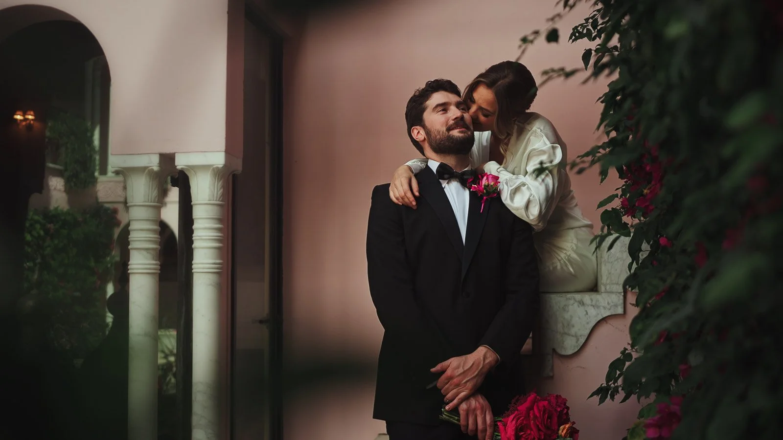 A bride kisses her groom in a courtyard surrounded by a bold colour palette and styling.