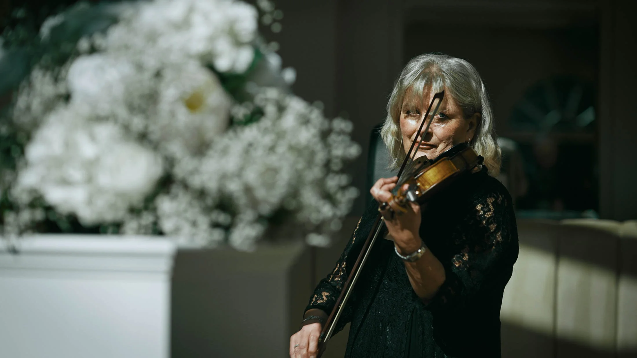 A cinematic-style shot of a violinist playing during an indoor wedding ceremony, taken from a storytelling wedding film.