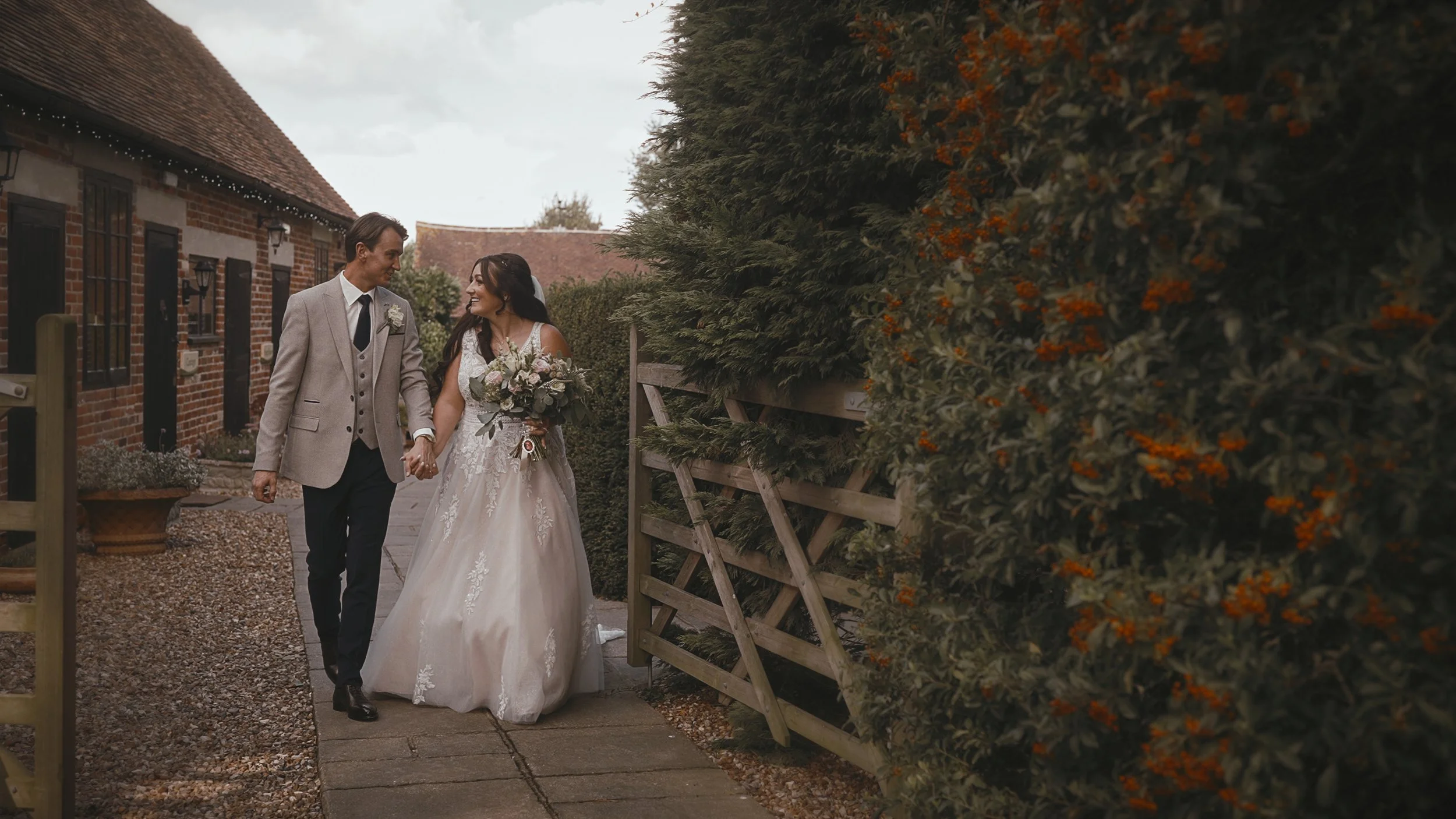 A couple walk through the grounds of Winters Barns in kent during their September wedding day.