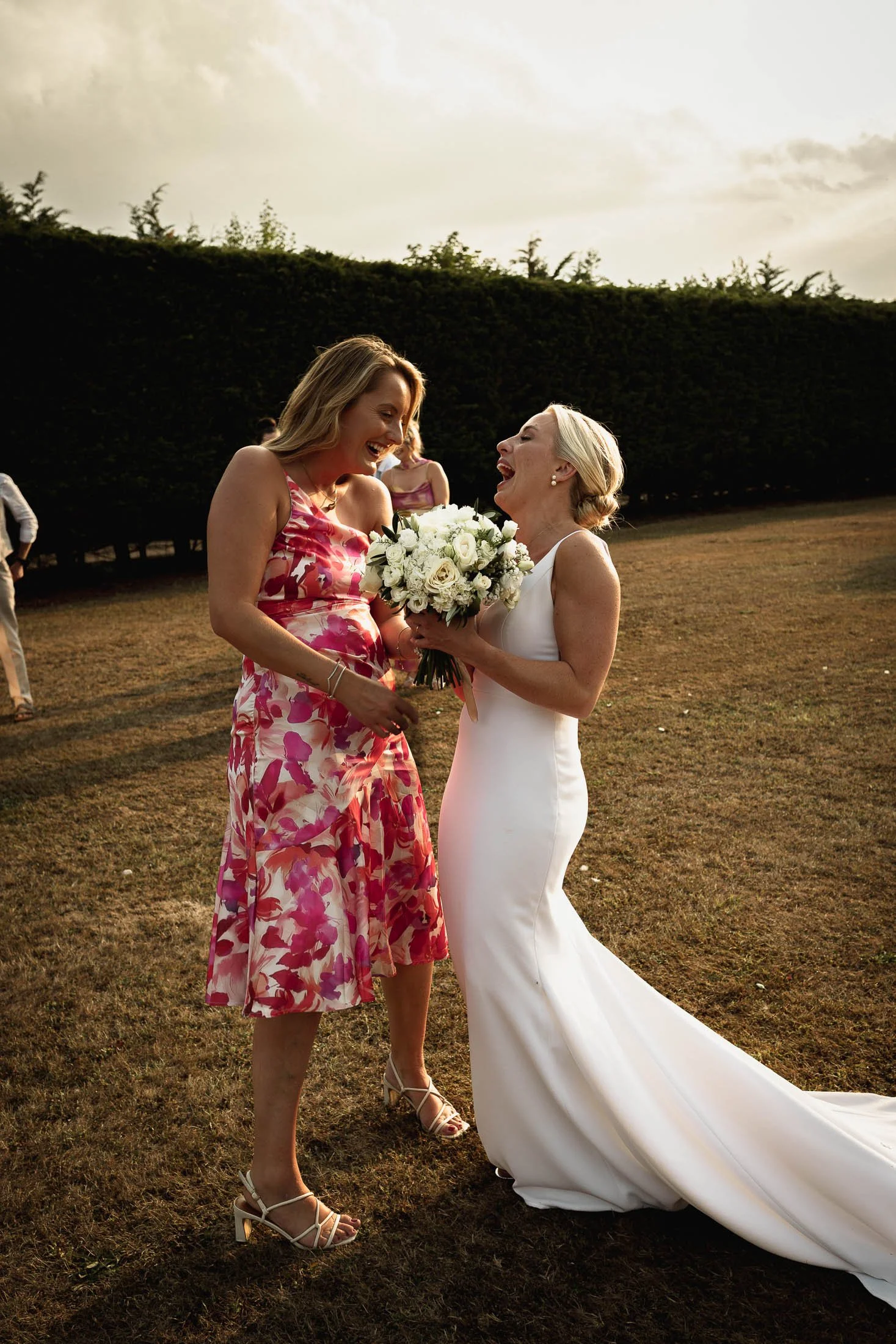A bride laughs with her friend who caught the bouquet at Winters Barns.