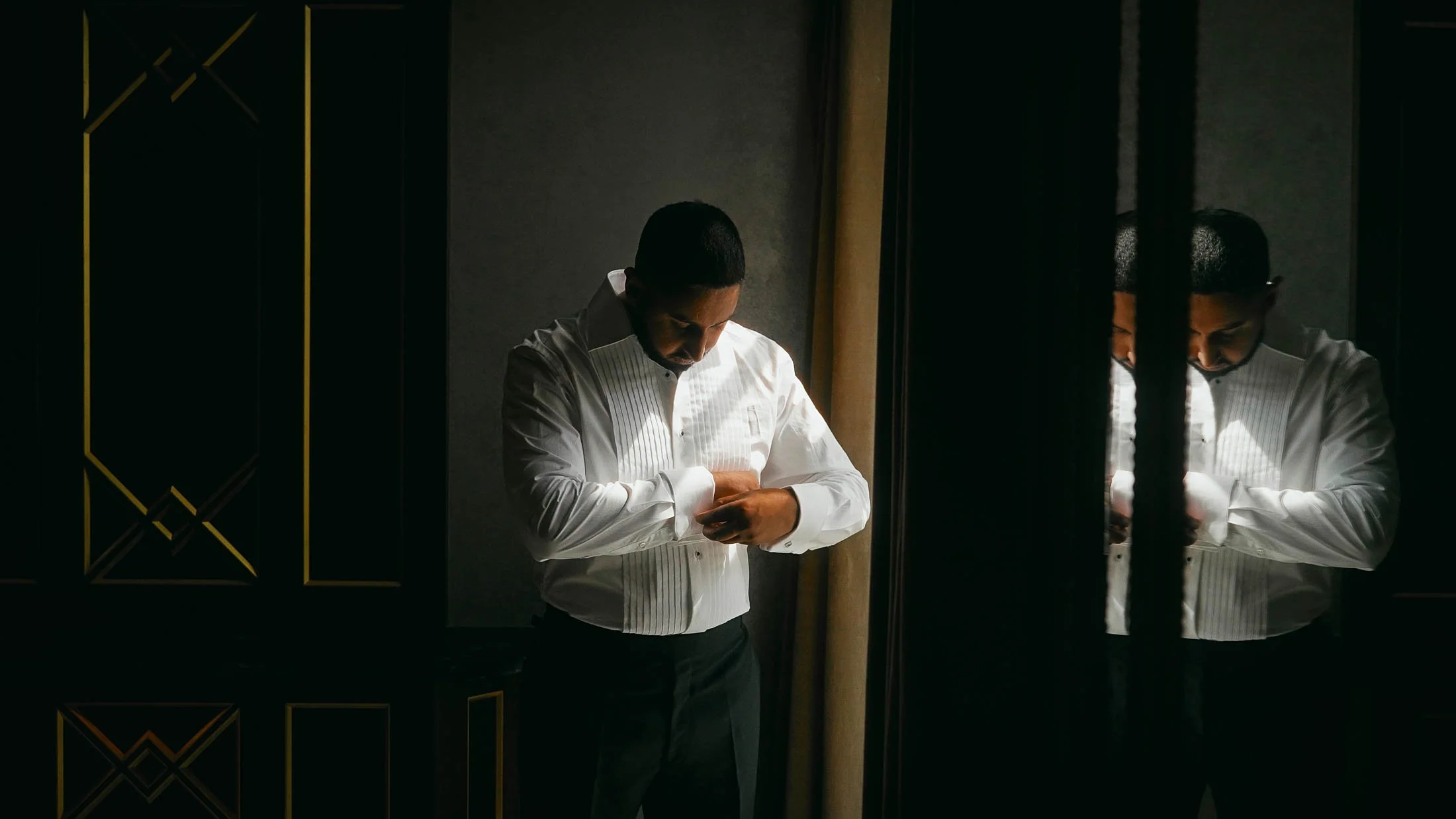 A groom fastens his cufflinks during morning preparations of his black-tie Grantley Hall wedding.