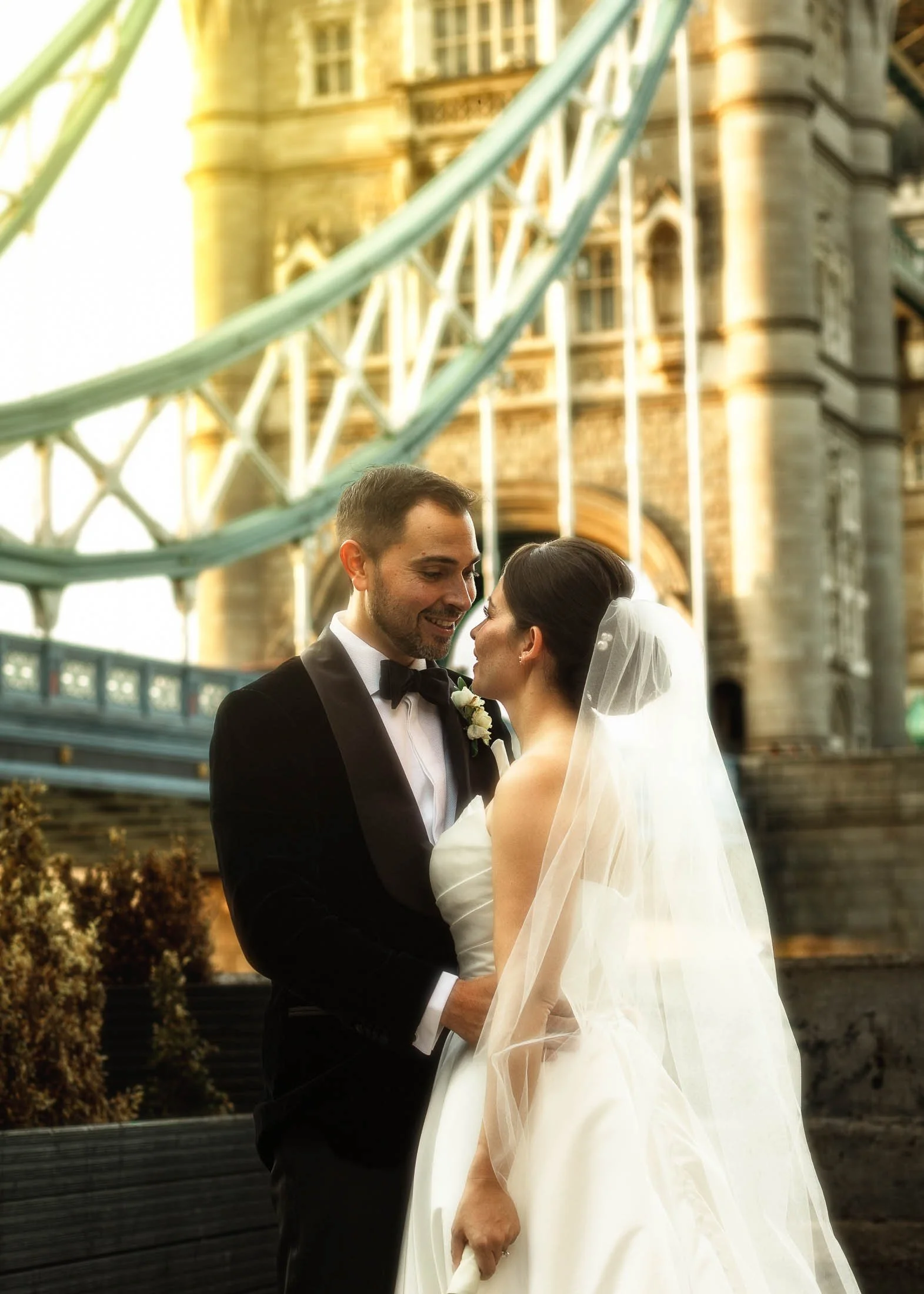 A couple pose intimately near Tower Bridge in London on their black tie wedding day.