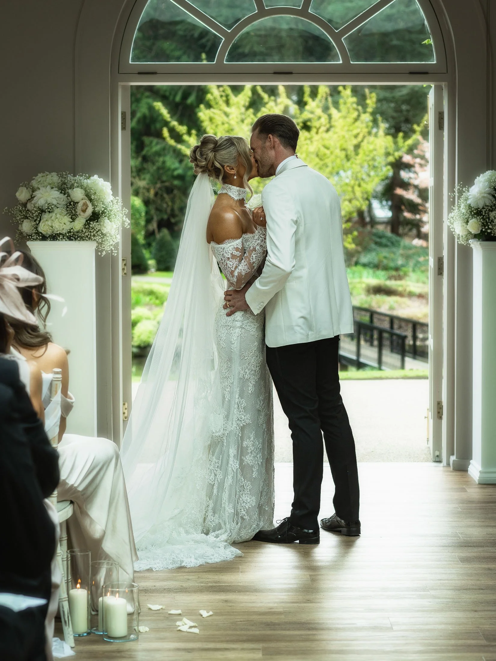 A couple share their first kiss as husband and wife during their luxurious indoor wedding ceremony at the Orangery Maidstone in Kent.