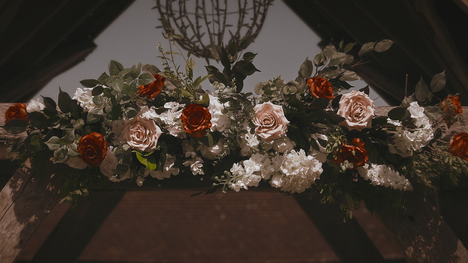 A white, orange and pink flower archway marks the netrance to a colourful outdoor wedding ceremony at Winters Barns.