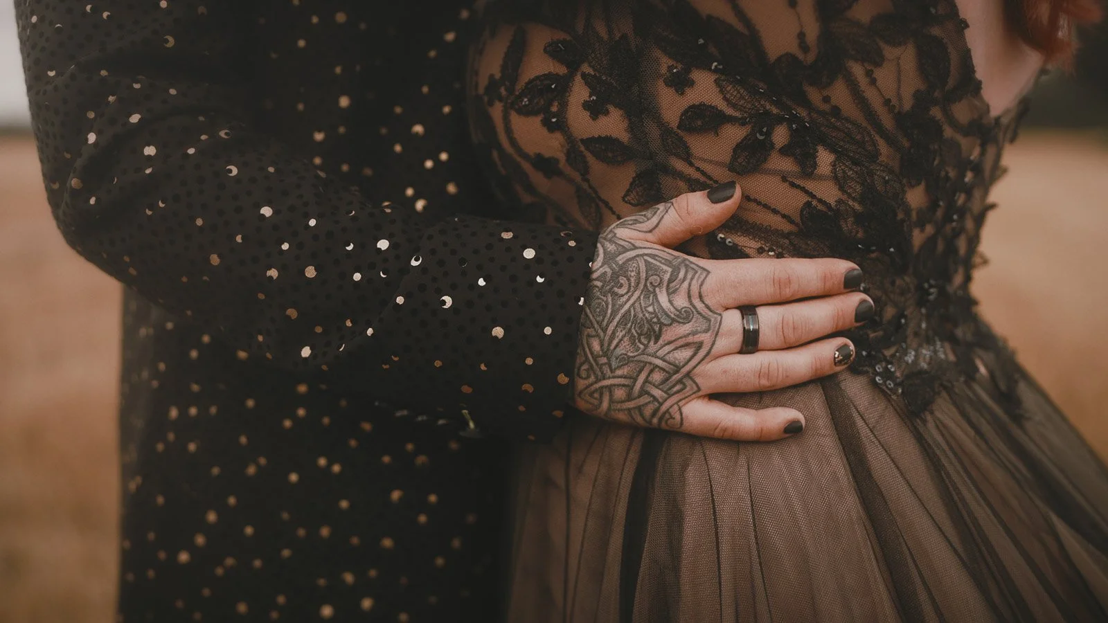 Close up details of an alternative wedding couples tattooed hands and black lace styling.