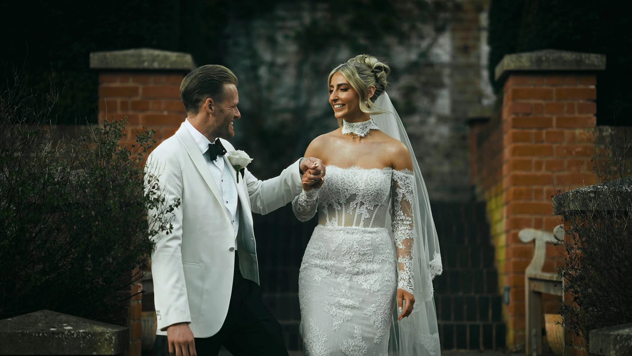 The groom holds the brides hand as she walks down stone steps in a quiet and intimate moment during their storytelling wedding film.
