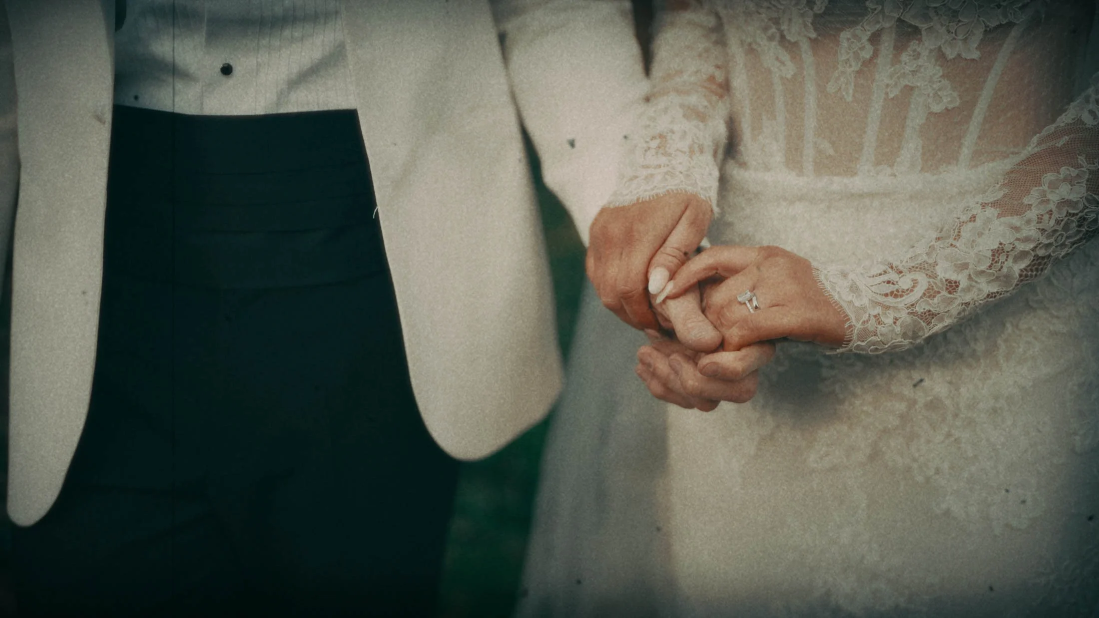 A brides hands holding the grooms hand, captured in a super 8mm emulation film stock look.