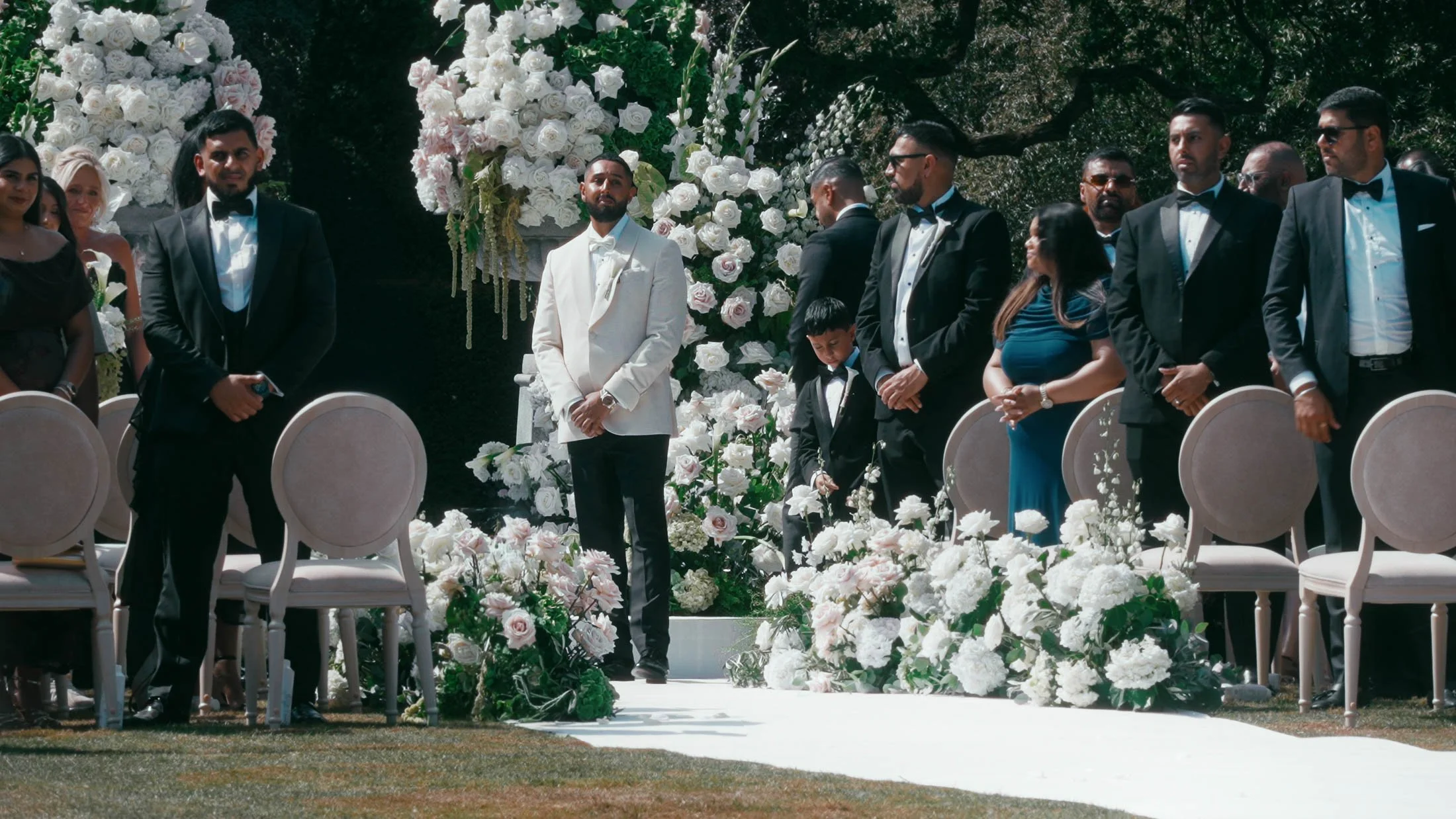 A black tie wedding ceremony outdoors at Grantley Hall in Yorkshire, as the groom turns around to see his bride for the first time.