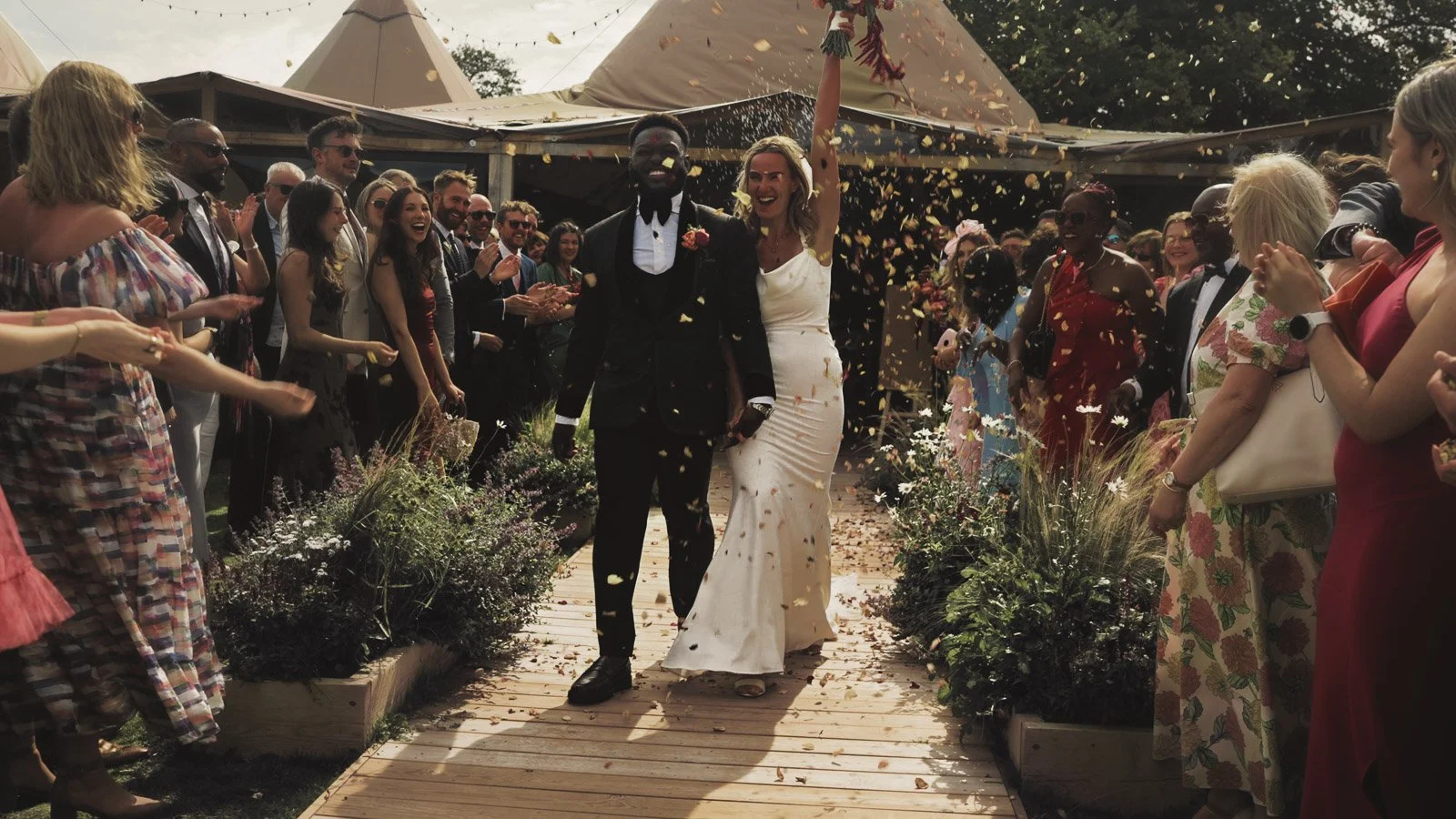 Confetti being thrown over the couple during a colourful riverside wedding ceremony by the River Thames at an Oxfordshire country estate