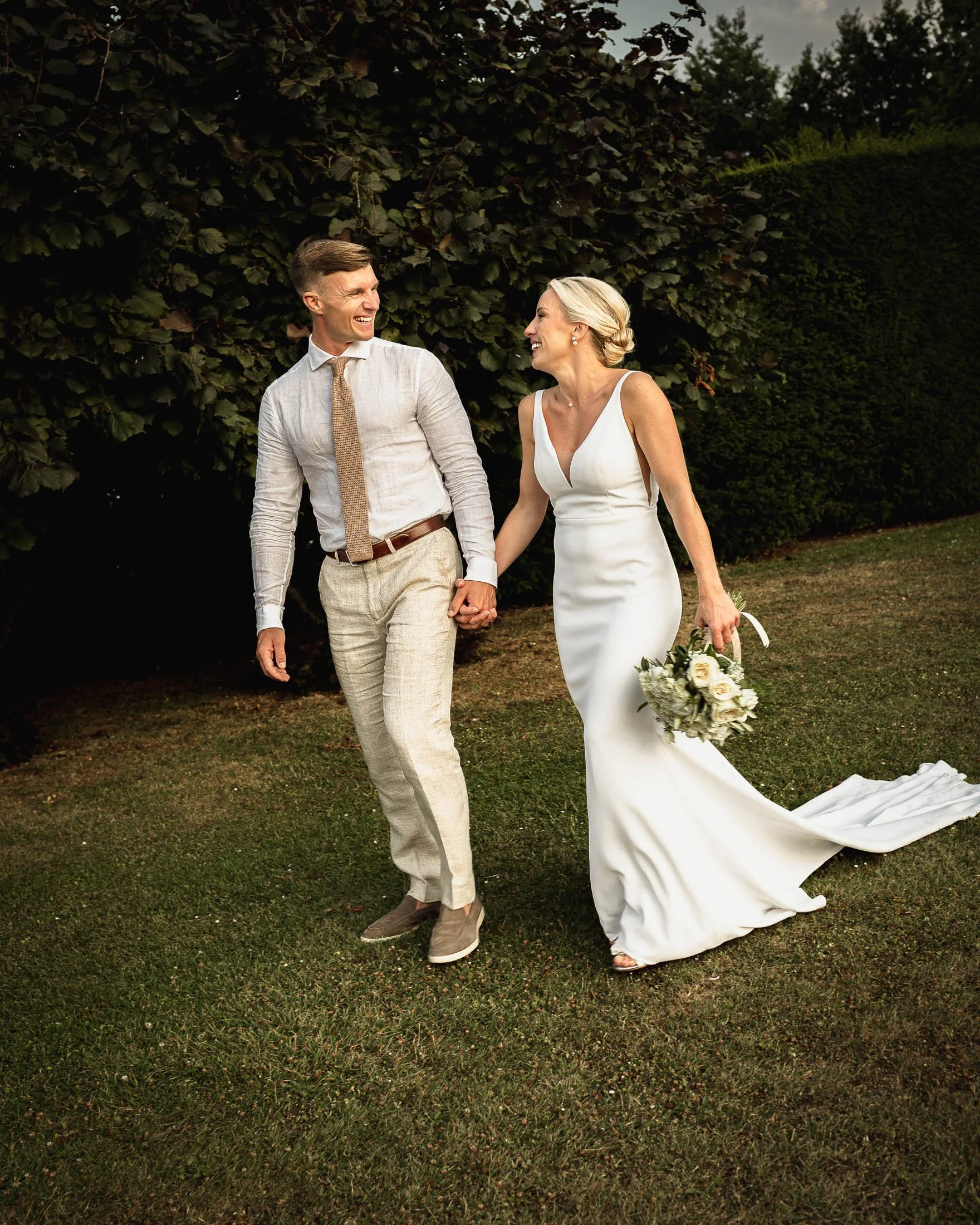 A bride and groom look at each other and laugh as they walk the grounds of Winters Barns.