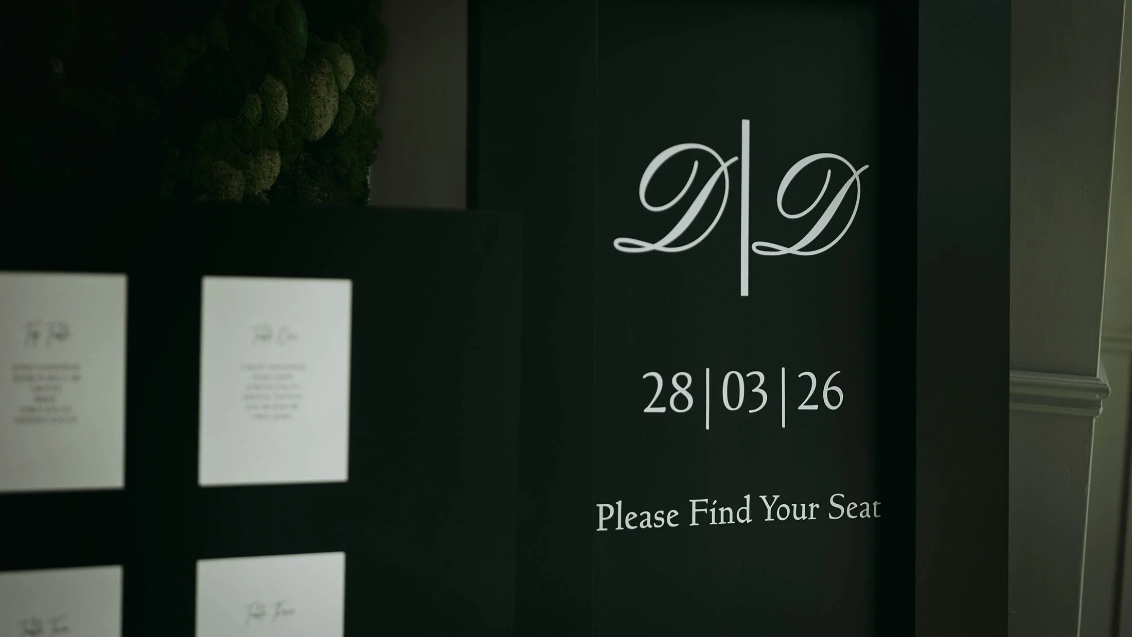 A black welcome sign with white writing sits in the entranceway of a black-tie wedding at The Orangery, Maidstone.
