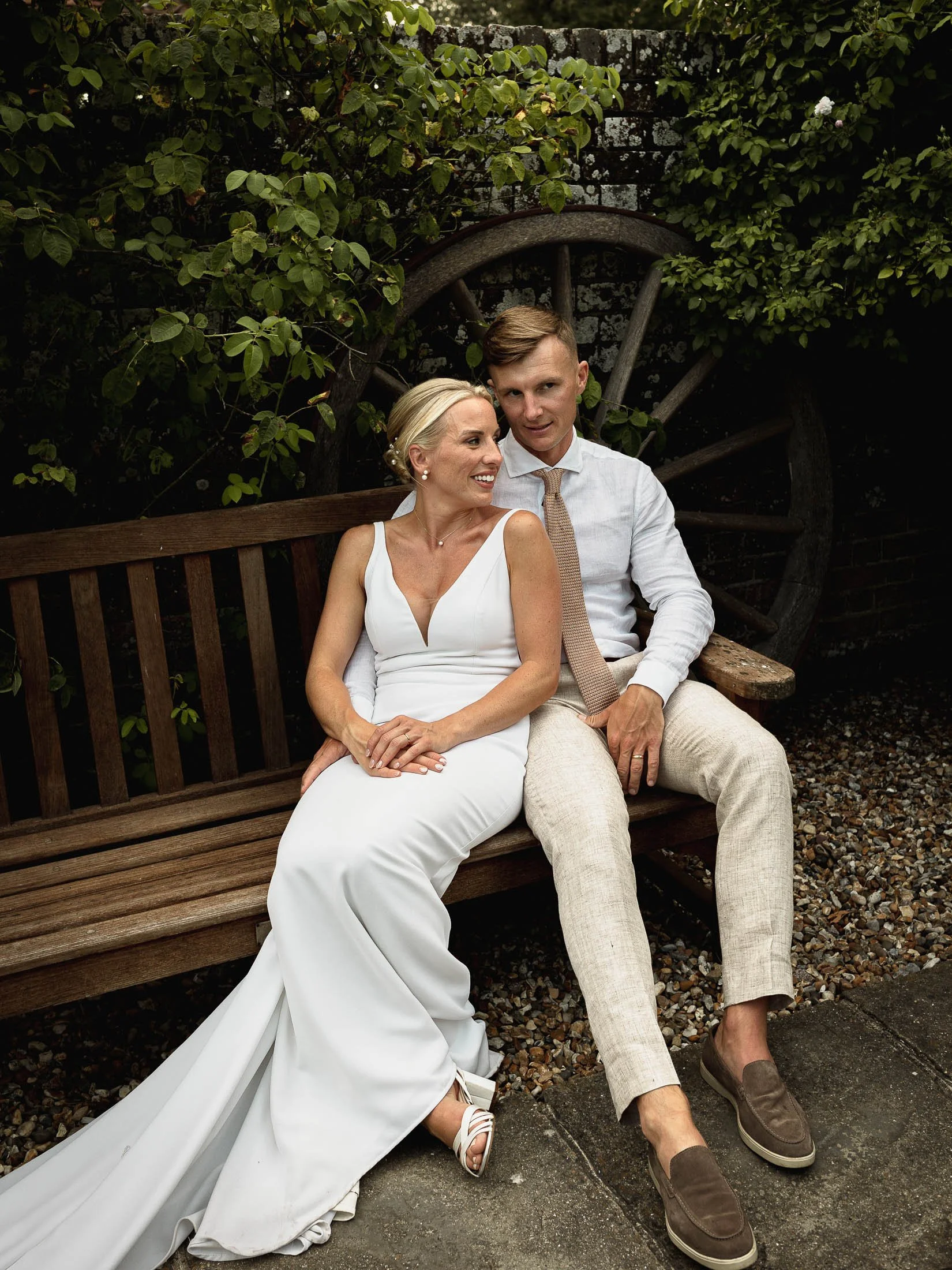 A relaxed moment between a bride and groom as they sit on a bench in the courtyard of Winters Barns in Kent.