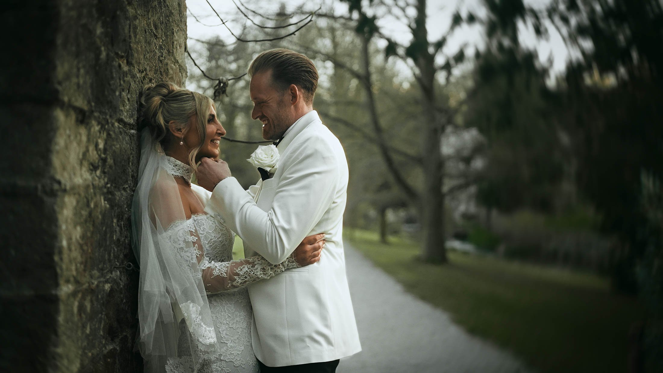 An intimate golden hour couples portrait as a groom in black-tie holds the chin of his bride, taken from their emotional storytelling wedding film.