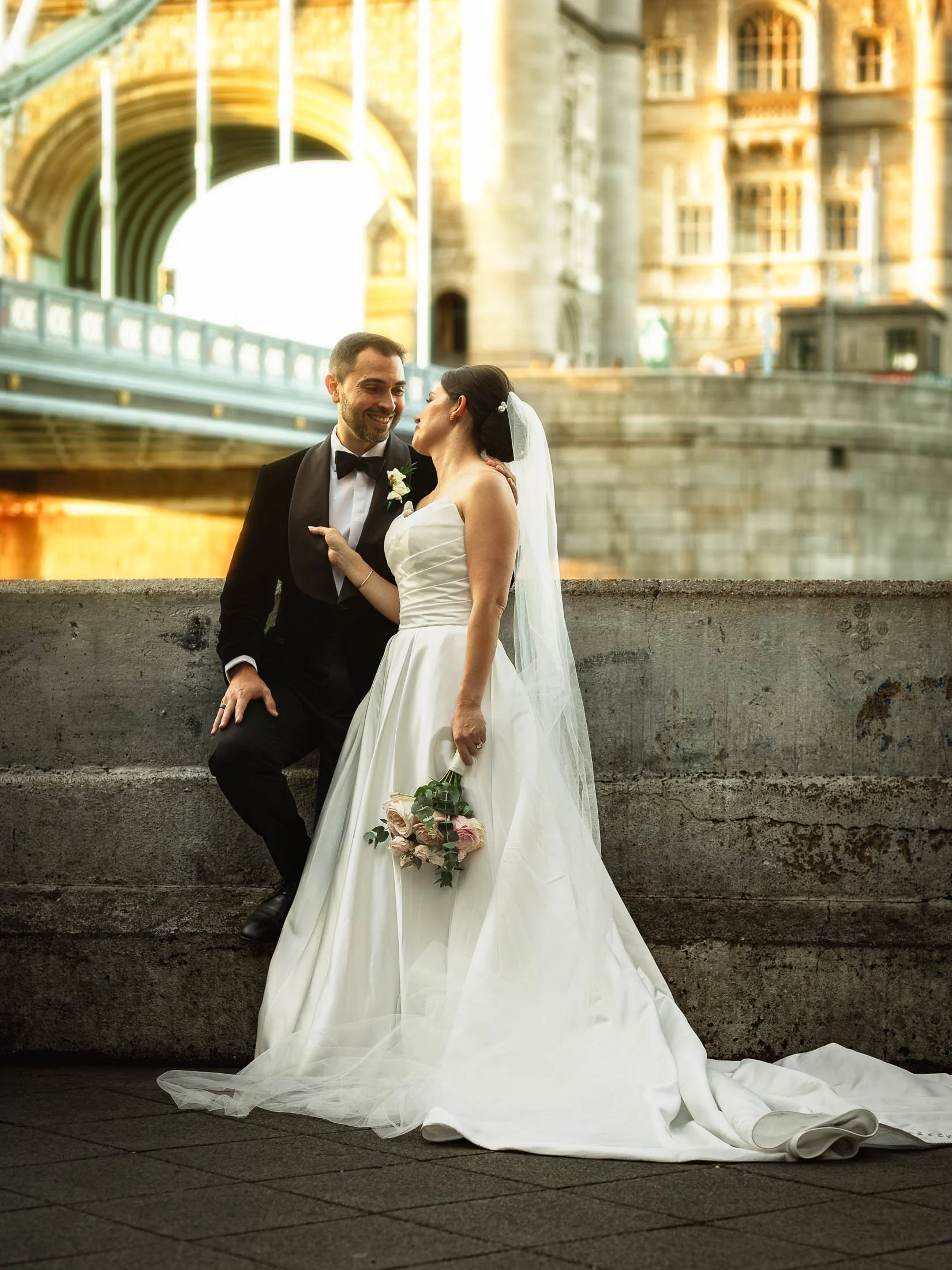 A romantic and editorial couples portrait with Tower Bridge in the background, taken during a black tie London wedding that was captured by a photography and videography team.