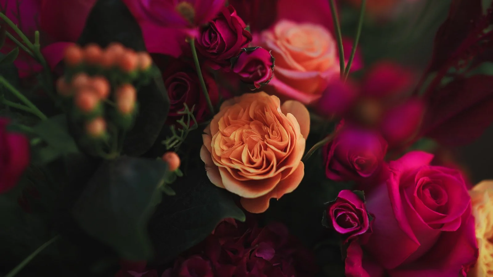 Close up detailed shot from a colourful fine art wedding film of bright pink and red floral setup.