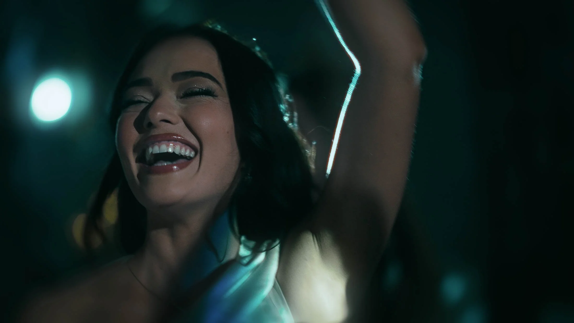 A close up shot of a bridesmaid laughing and dancing during evening celebrations.